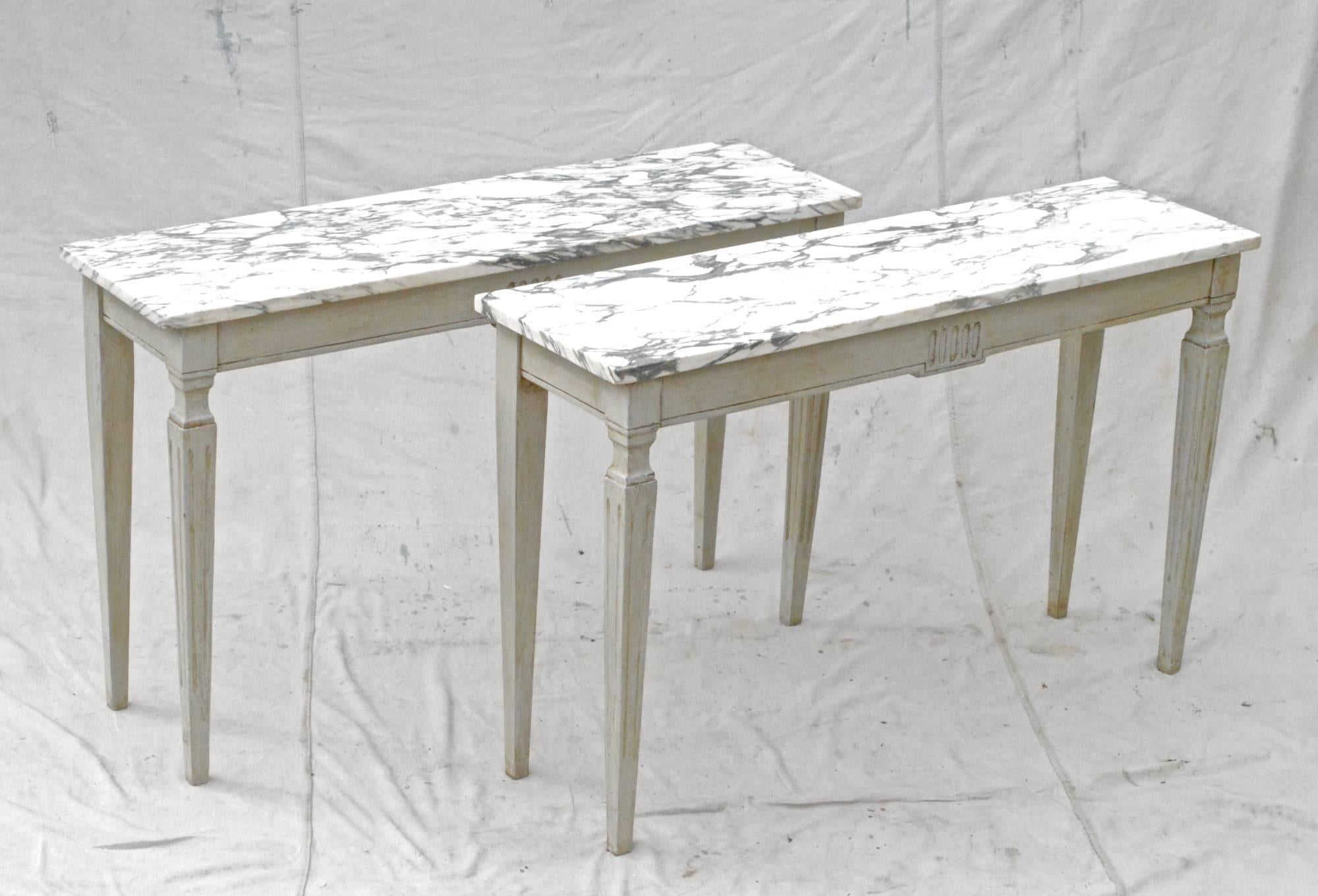 Pair of Louis XVI styled consoles having elegant marble tops and strong, simple lines throughout. On both tables, the paint has recently been updated.