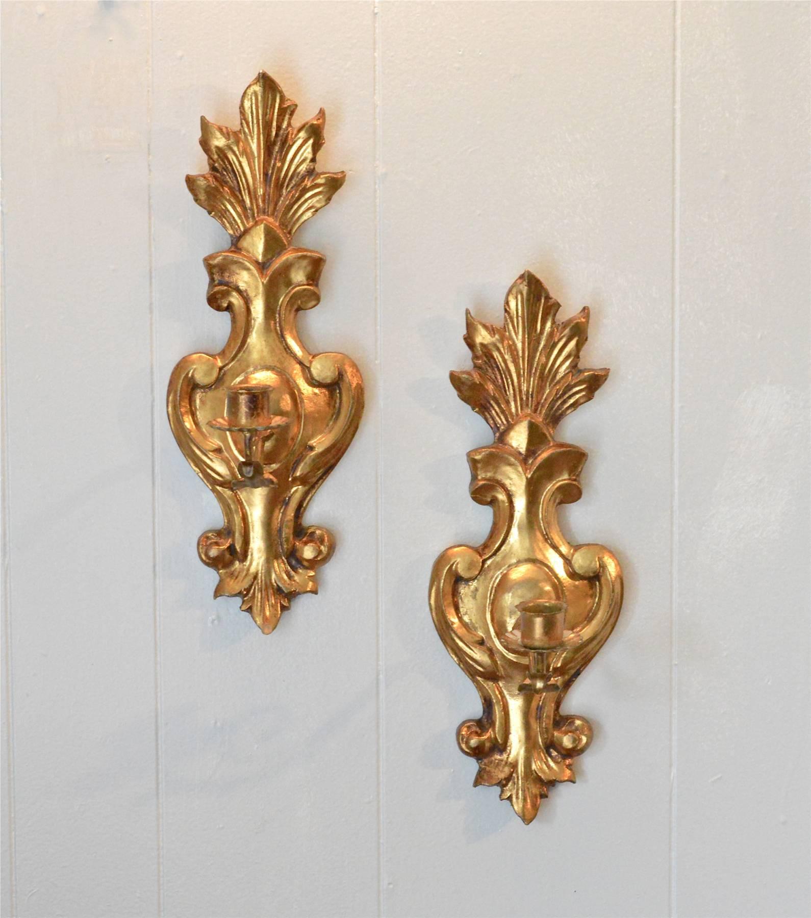 A pair of Italian wall-mounted sconces of Fleur de Lis form. Non-electrified, the water gilt, carved wood forms are simple and stunning. Made in Italy stamps to the back, circa 1960.