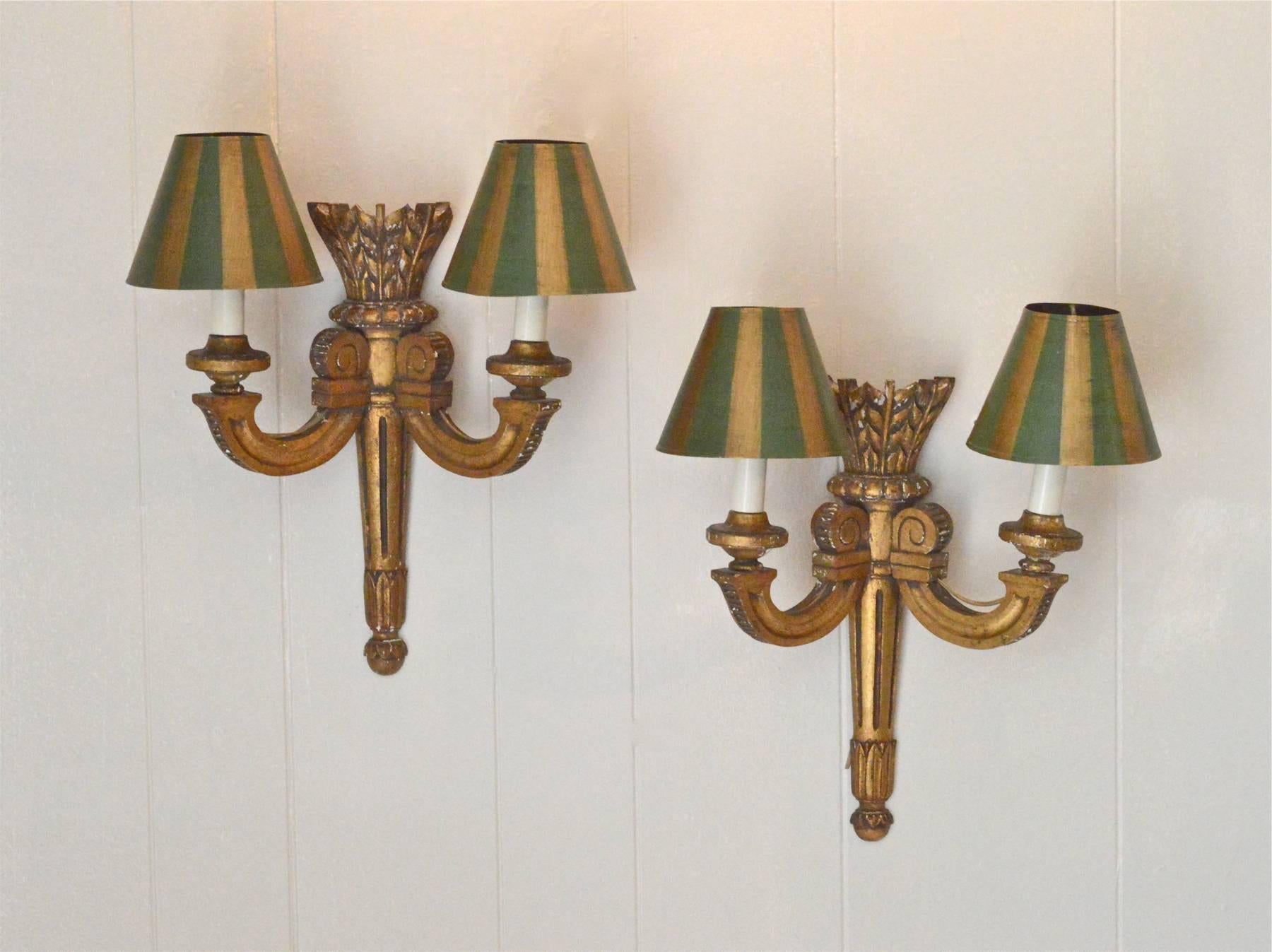 A superb pair of carved giltwood sconces in the Louis XVI taste. The pair are adorned by hand-painted tole' shades in green and gold. Electrified and in working order, these late 19th century sconces will transform any space in which they are