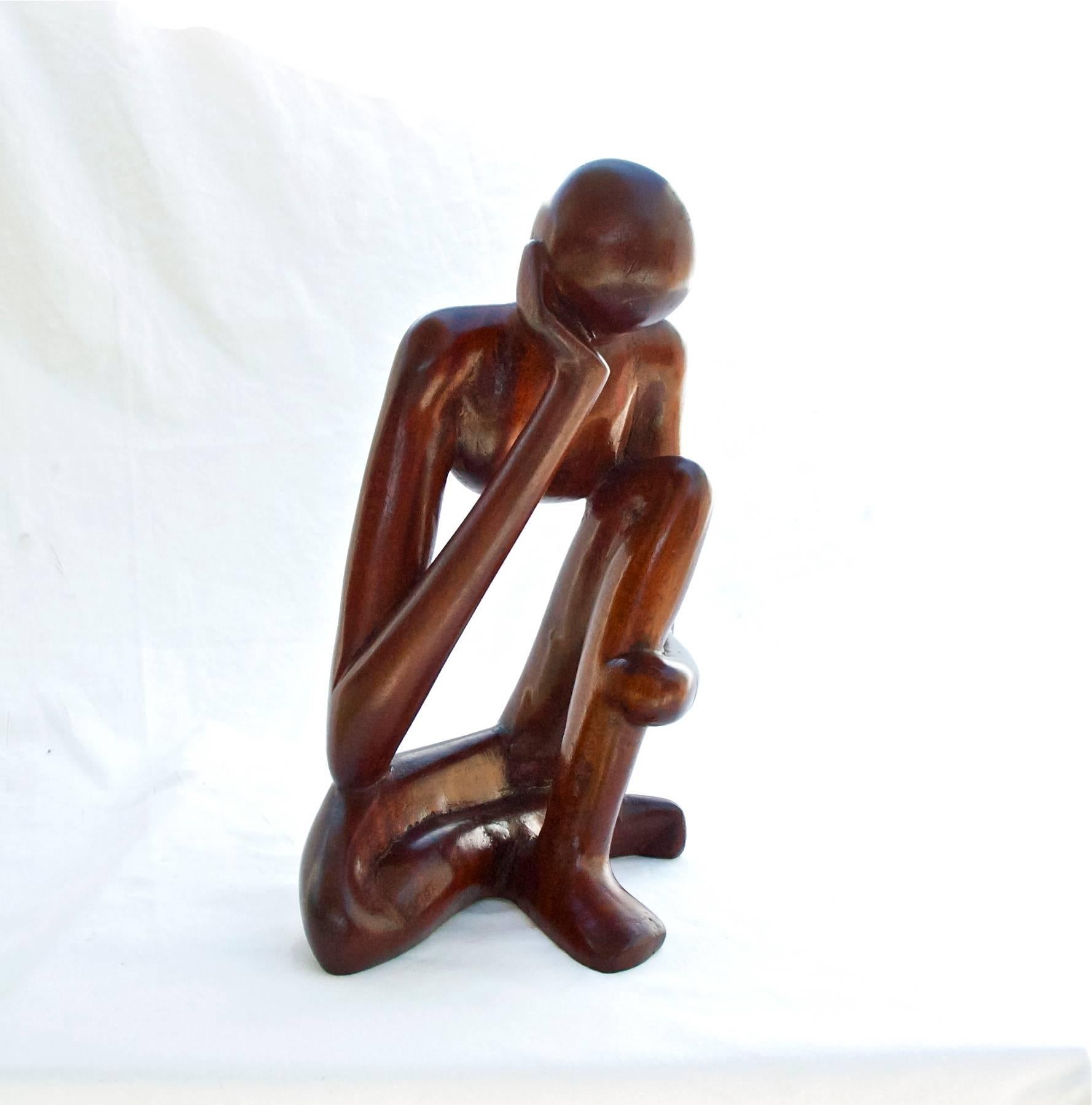 Modernist sculpture hand-carved and worked of mahogany. The figure sits in contemplation with head slightly bowed, suggestive of an existential crisis. Unsigned.