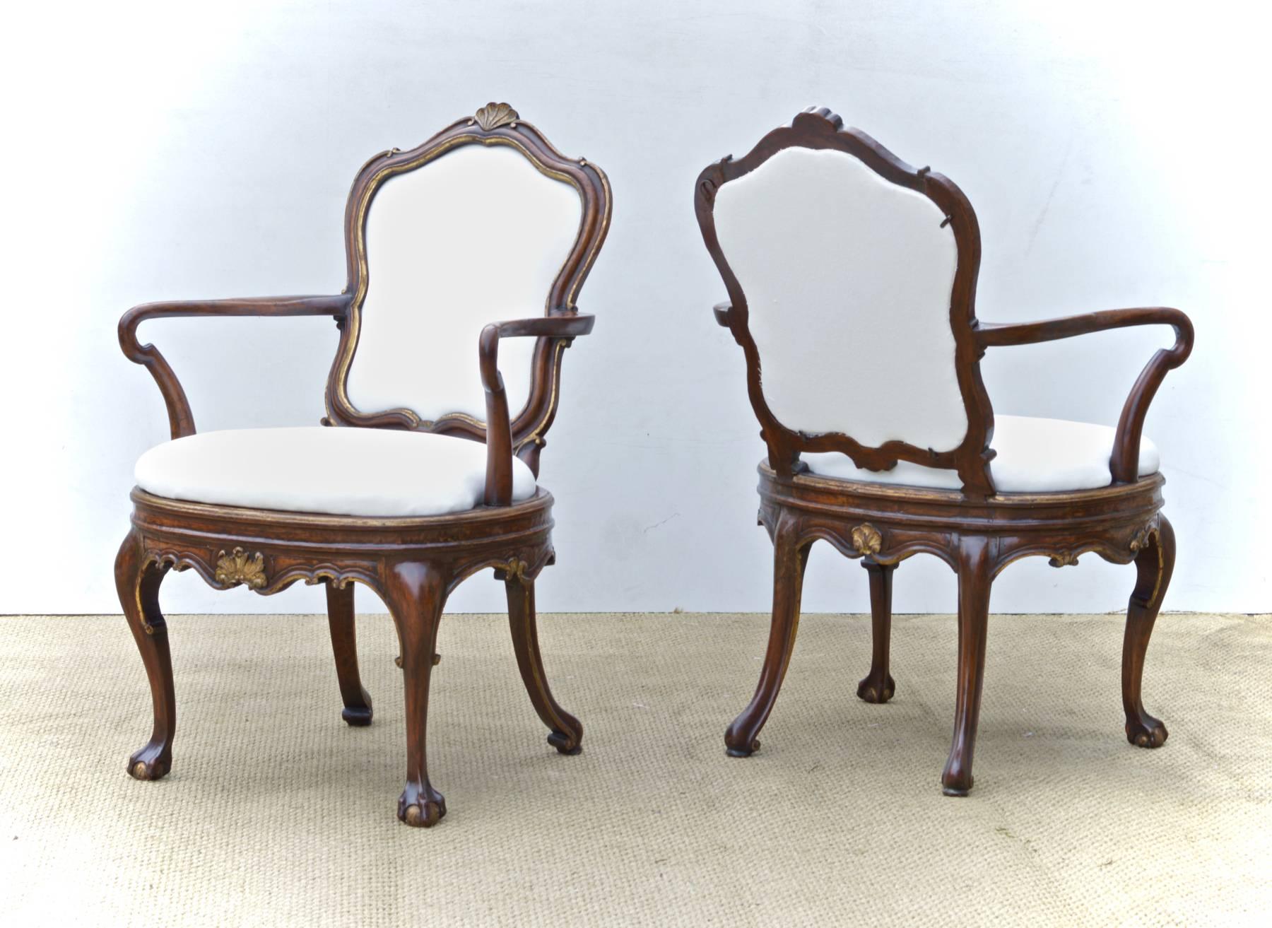 A spectacular pair of Italian walnut armchairs in the venetian taste with gorgeous parcel-gilt accents and captivating ball and claw feet. The late 19th century chairs have just been simply upholstered in white duck. Nice sitting chairs. Both are