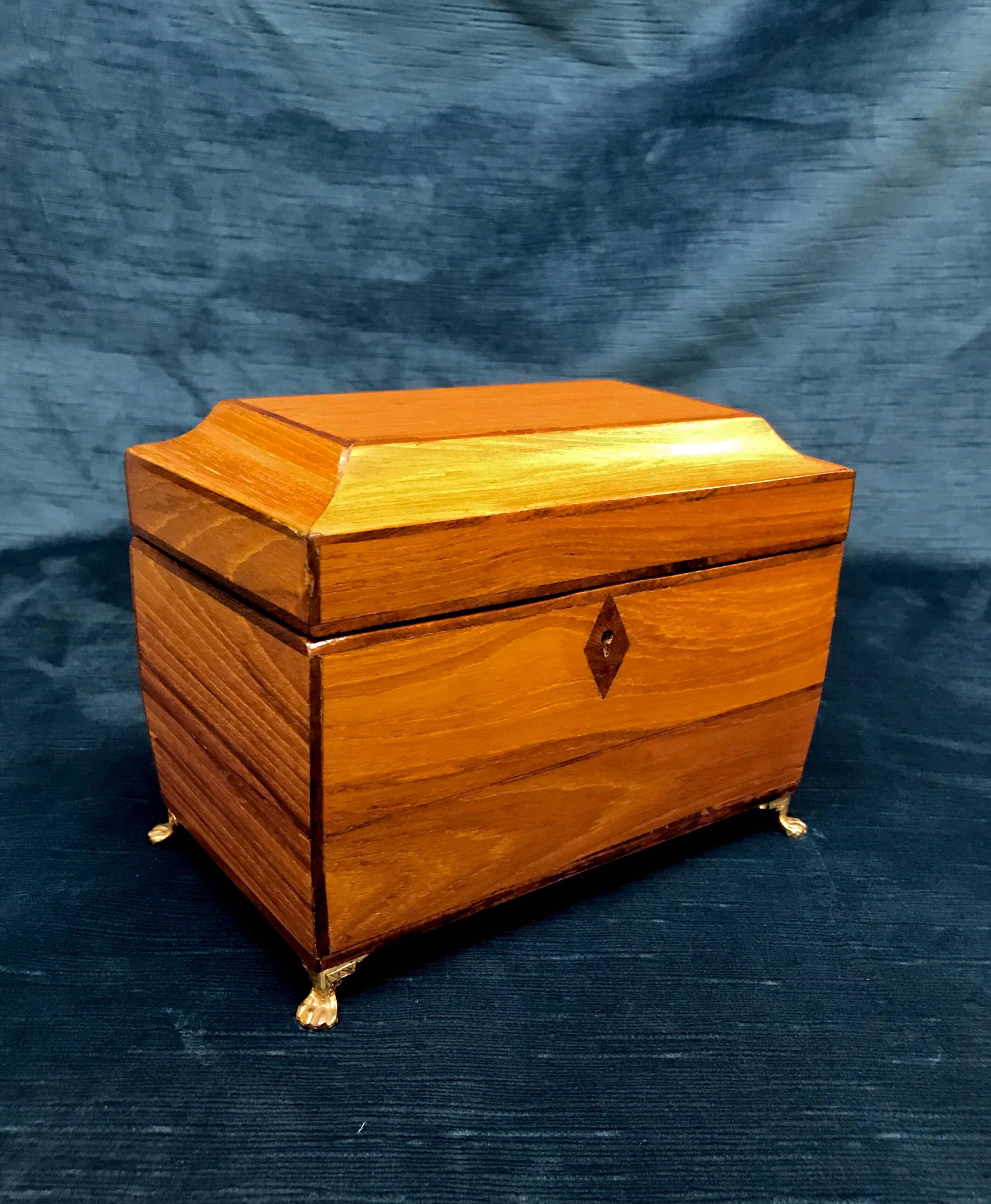 Late 19th century Regency tea caddy of a small size. The sarcophagus formed container is composed of oak and trimmed out in mahogany and ebony woods. The hinged box opens to reveal flanking and lidded storage cells which can readily store tea,