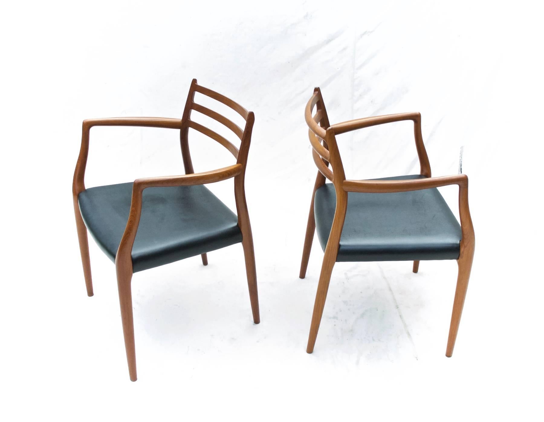 A fine pair of model 62 dining chairs by N.O. Moller. The gorgeous and sculptural Danish Modern armchairs are in excellent structural condition throughout and possess a richness of wood grain that set them apart from other teak wood models of this
