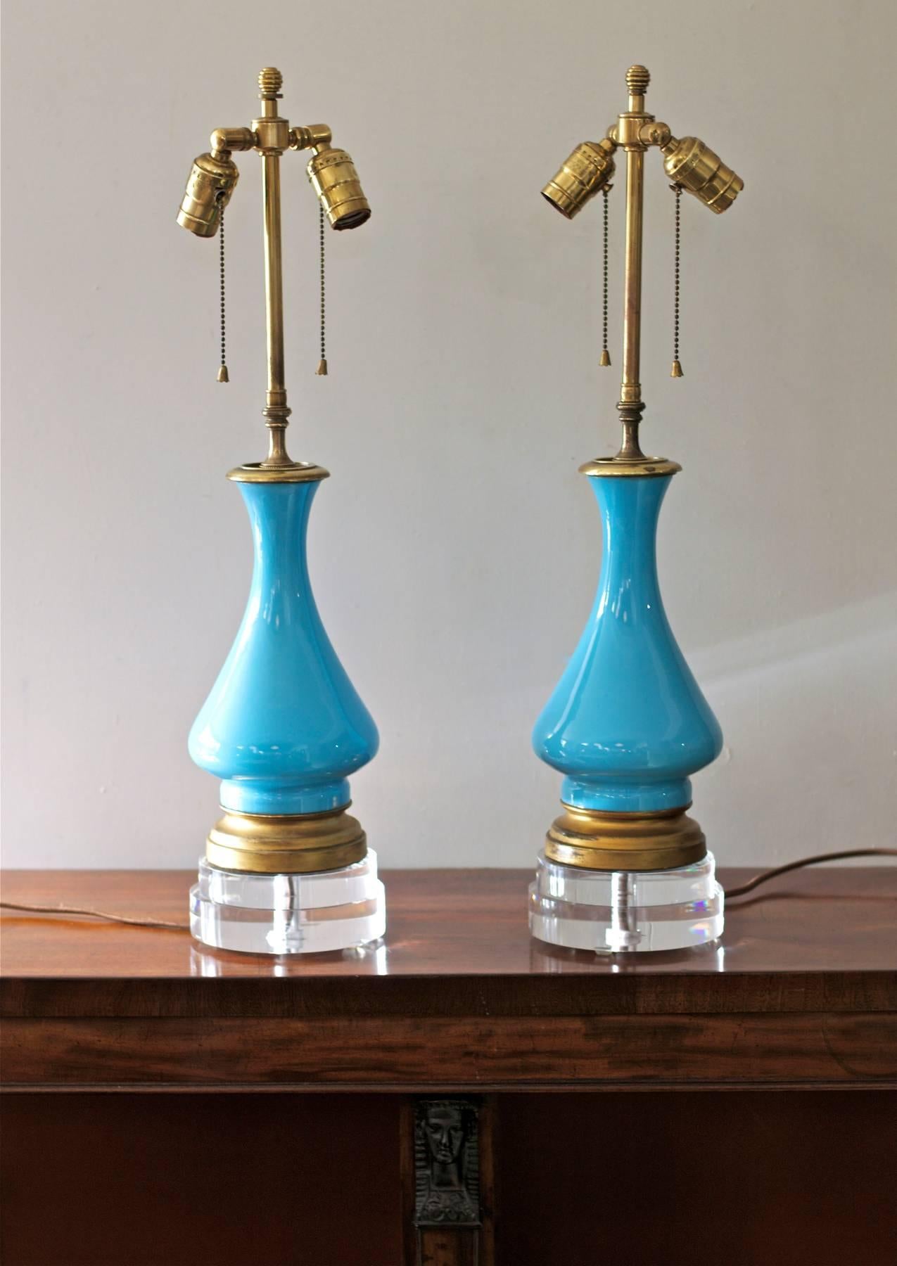 A gorgeous pair of French blue opaline glass lamps riding in style on custom cut lucite bases and retrofitted with vintage brass double cluster sockets. Newly wired with brown silk wrapped cords. 