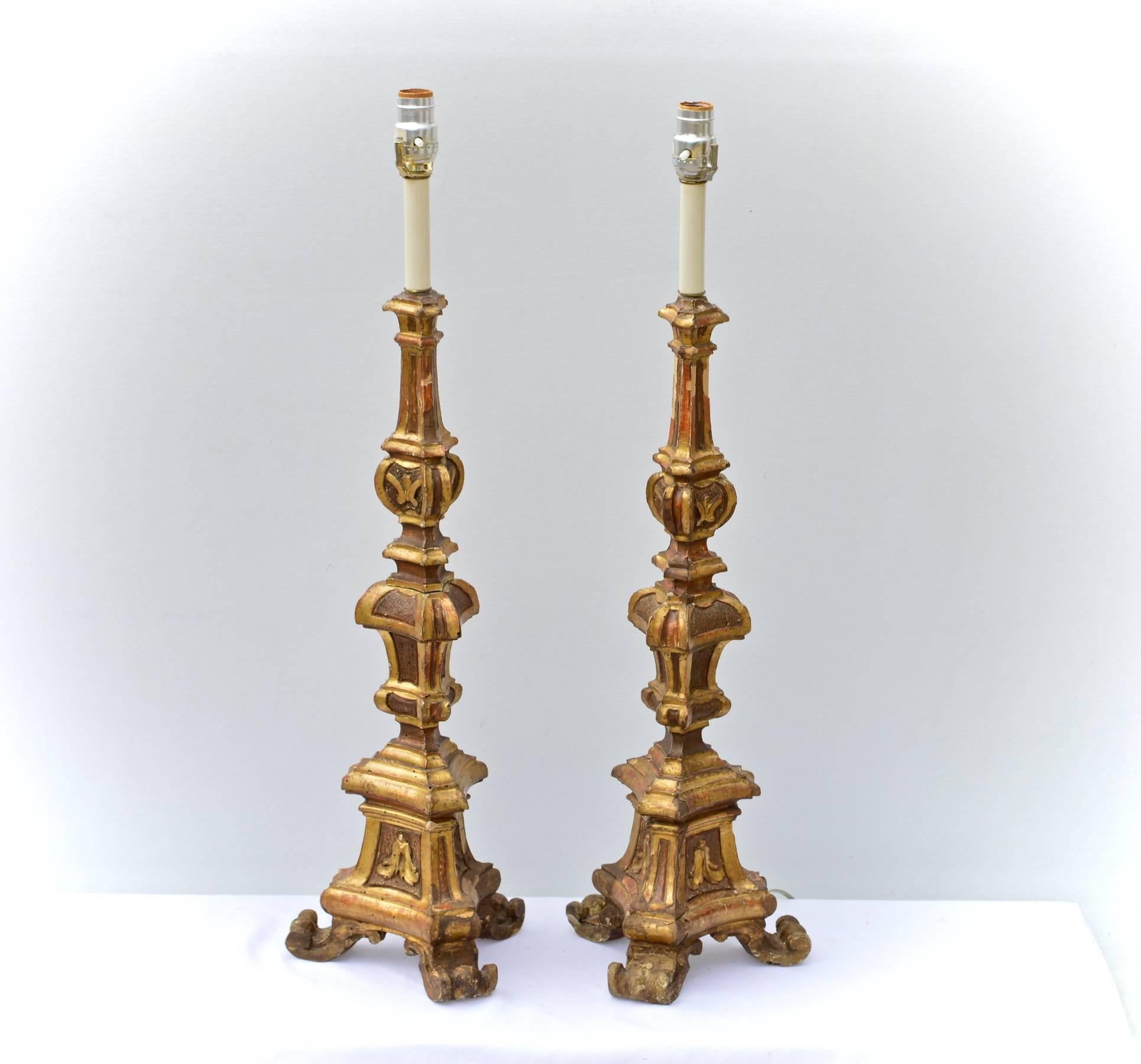 A stunning pair of early 19th century Italian pricket sticks or candlesticks that have been converted to electrified table lamps of large a present scale. The hand-carved forms show a deep gold lustre and patination that only time may truly achieve.