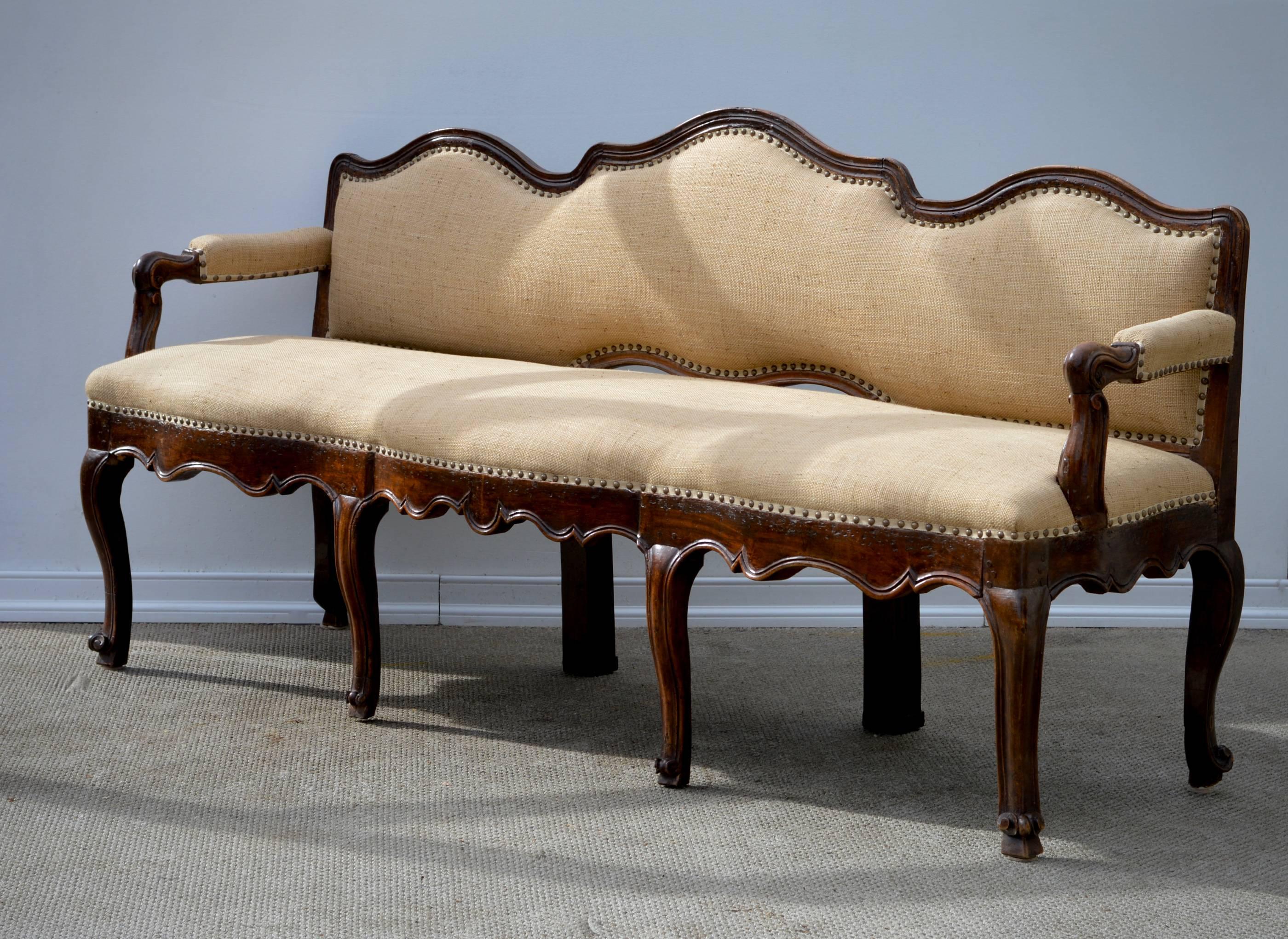 A charming and unusual Italian hall bench of walnut, circa 1780 in the Louis XIV Provincial taste. The triple back hand-carved settee is of a rare shape and in so, possesses a tremendous amount of style and will surely transform any space in which