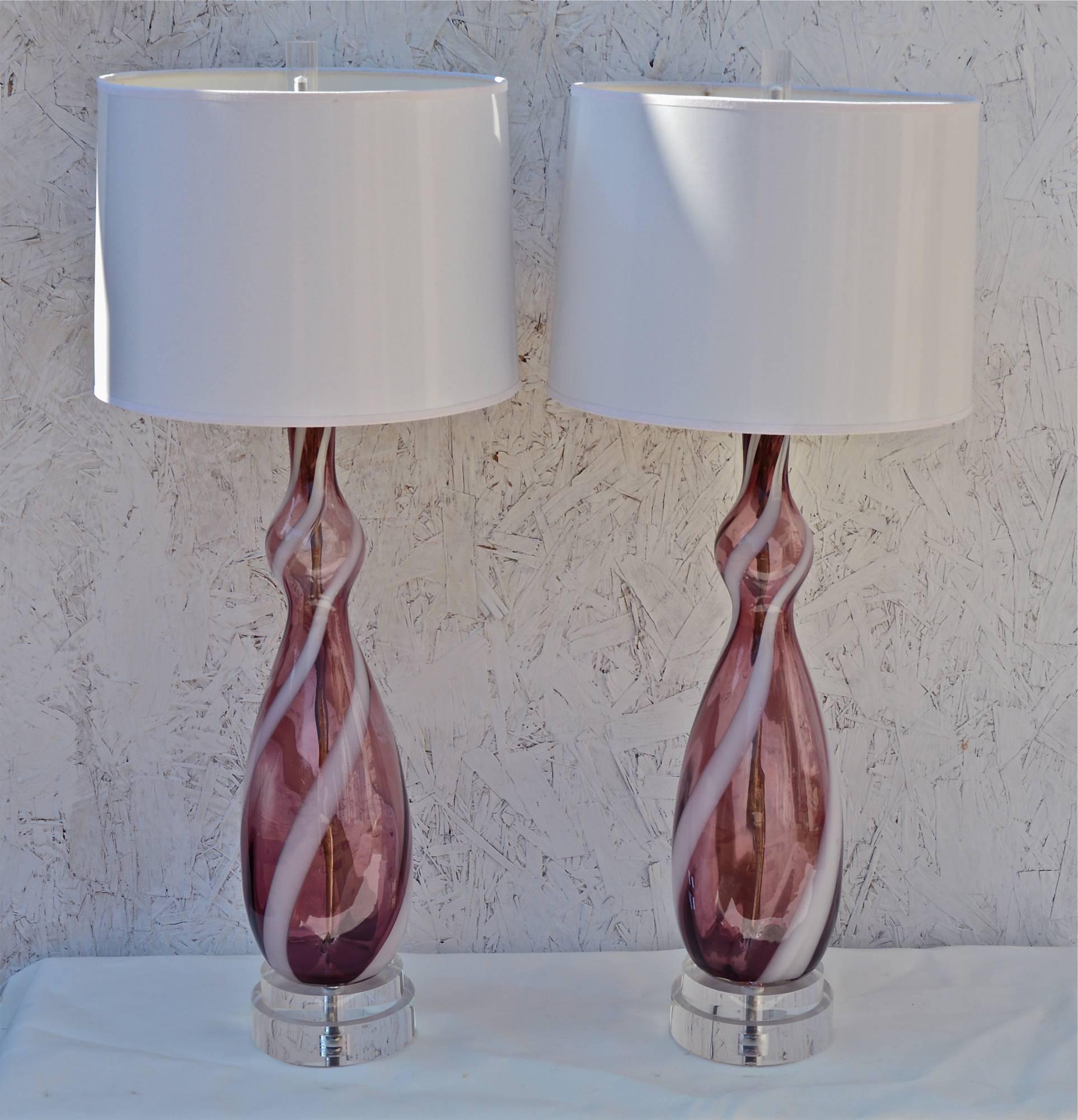 Pair of Mid 20th Century Italian murano glass lamps of light aubergine having applied white ribbon swirls. The matched pair of purple glass forms are mounted on custom double stack lucite bases. Nickel double clusters up top for the works. Lamps