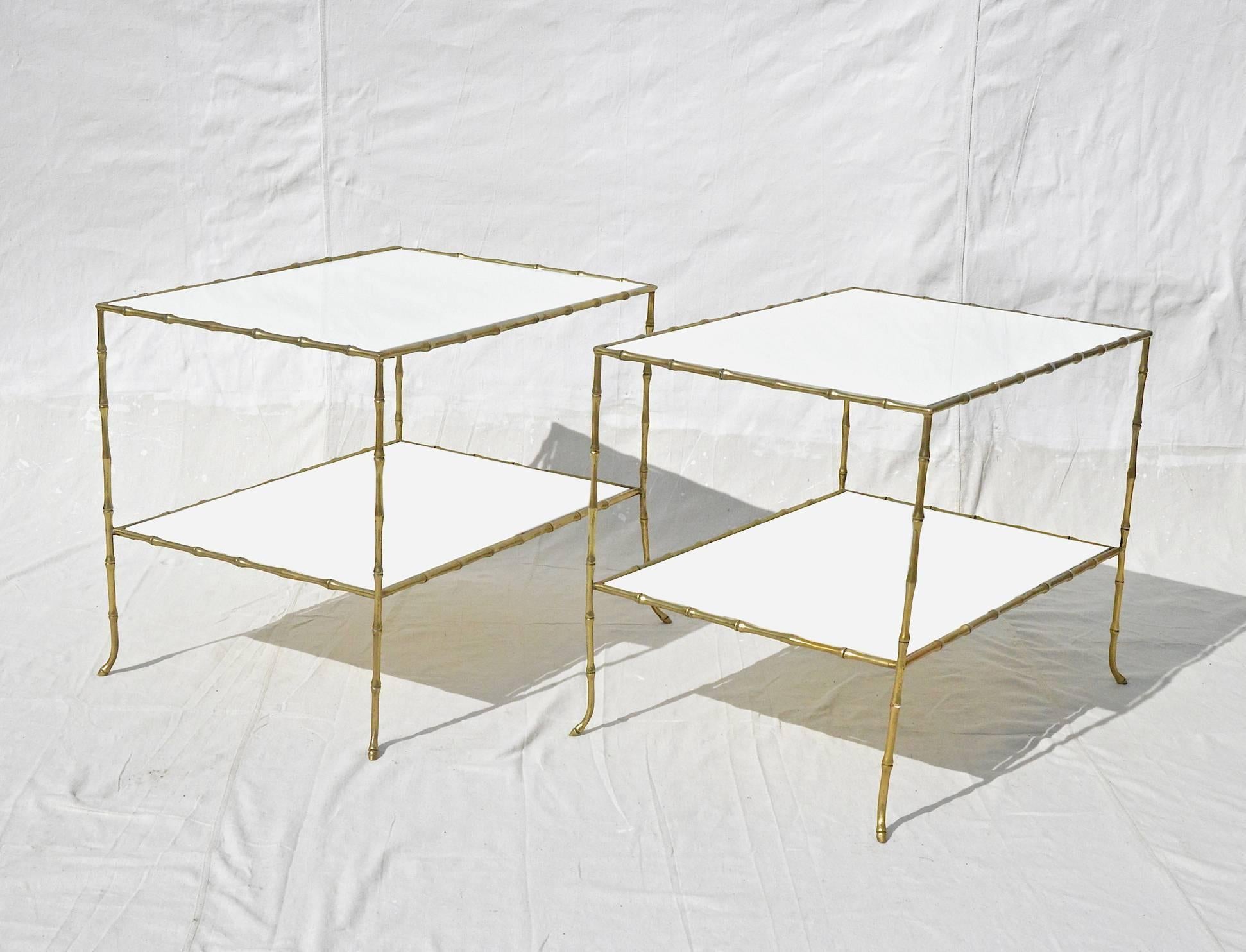 Faux bamboo table pair in the manner of Maison Bagues. The circa 1950's tables sport incredibly cast faux bamboo work and refined horse hoof feet. Two-tier original white milk glass tops adorn both tables. Mid-20th century refinement at its