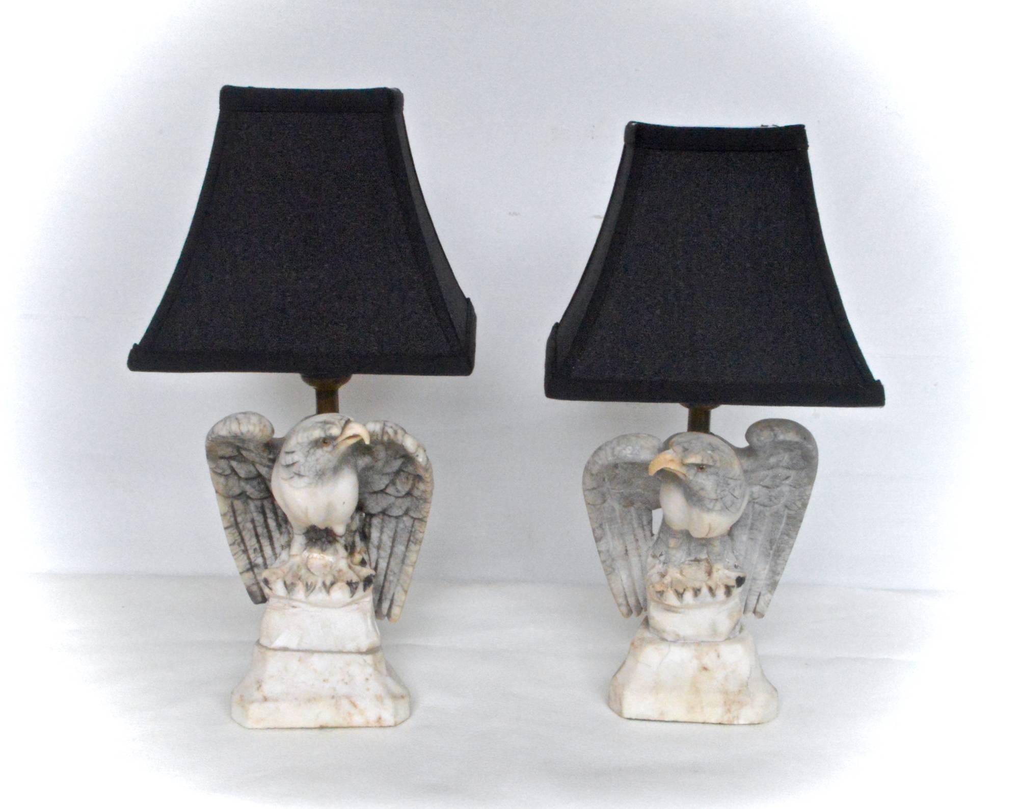 A near pair of carved marble lamps depicting fierce eagles. In the Art-Deco taste, these wonderful little lamps are a stylish addition to any classically inspired decor. Rewired in brown cloth wrapped cords, lamps sell and ship with the pictured