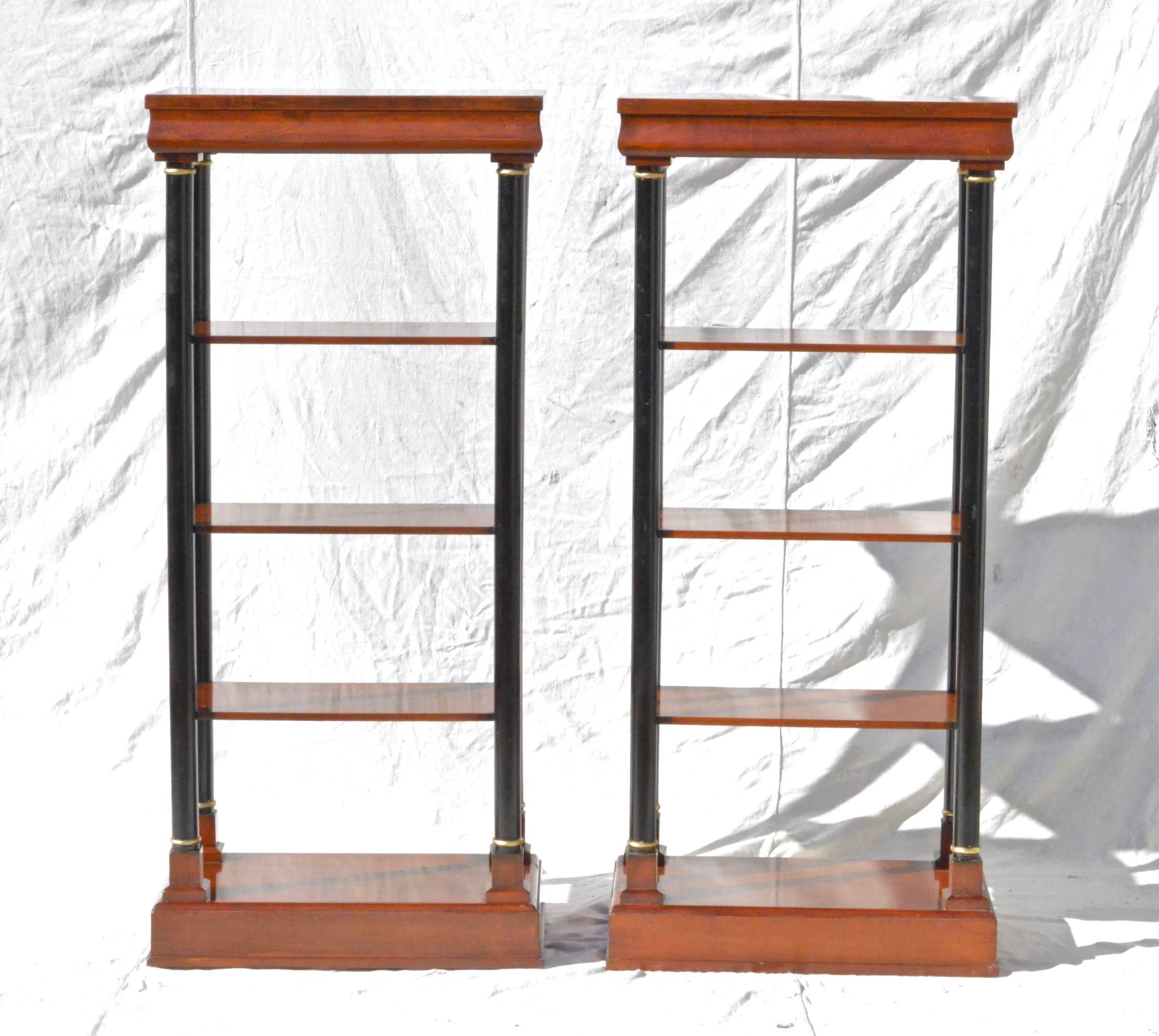 A pair of neoclassical styled Etagere in fruitwood having top drawers, three open shelves each, and a lower shelf that resides upon the base. The ebonized columns on each unit are visually striking and really give these vintage pieces a tremendous