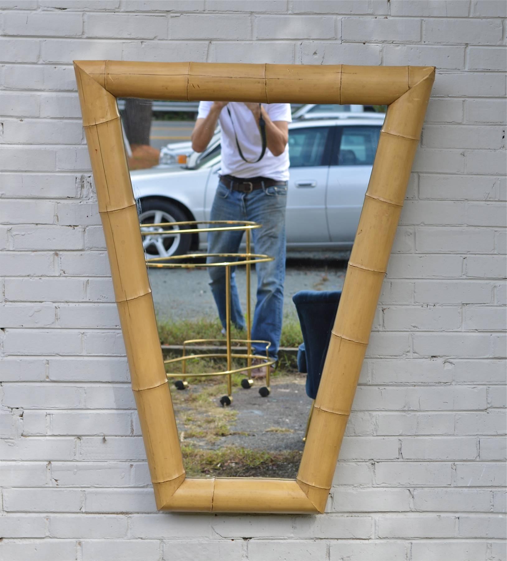 A dramatic vintage bamboo form mirror of trapezoidal shape. The chunky cast body of this cool mirror give it some playful scale and will make it easy to place within any modern interior. 
37" wide at the top 
18" wide at the bottom.