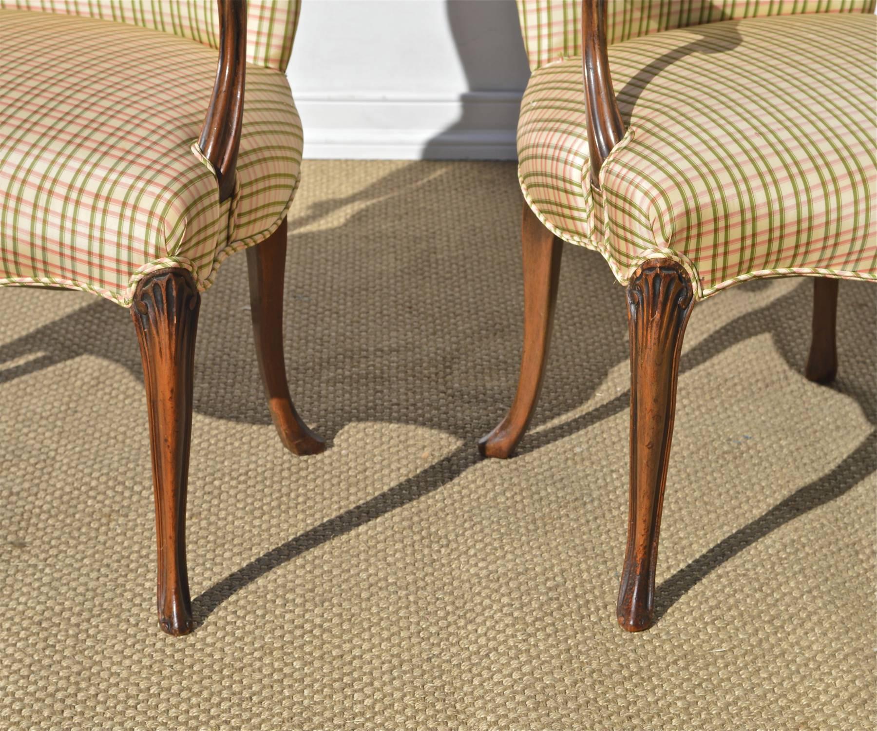 A fantastic pair of carved fruitwood library chairs in the Georgian taste dressed up in an iconic Brunschwig & Fils silk check of cream, pink and green. Traditional seating is always in fashion. The chairs sit well and are inviting. Two-three tears