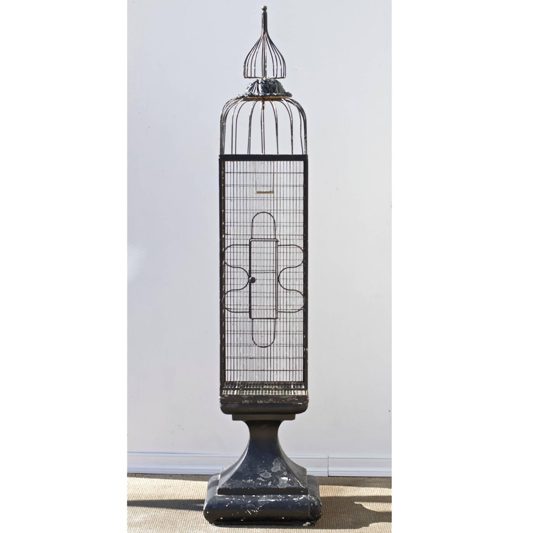 A tall and architectural metal birdcage on fiber cast stand. The look is highly decorative with a rustic edge. The design of the birdhouse is distinctively in the manner of Frederick Weinberg. Equally at home inside or outside any fine home. 