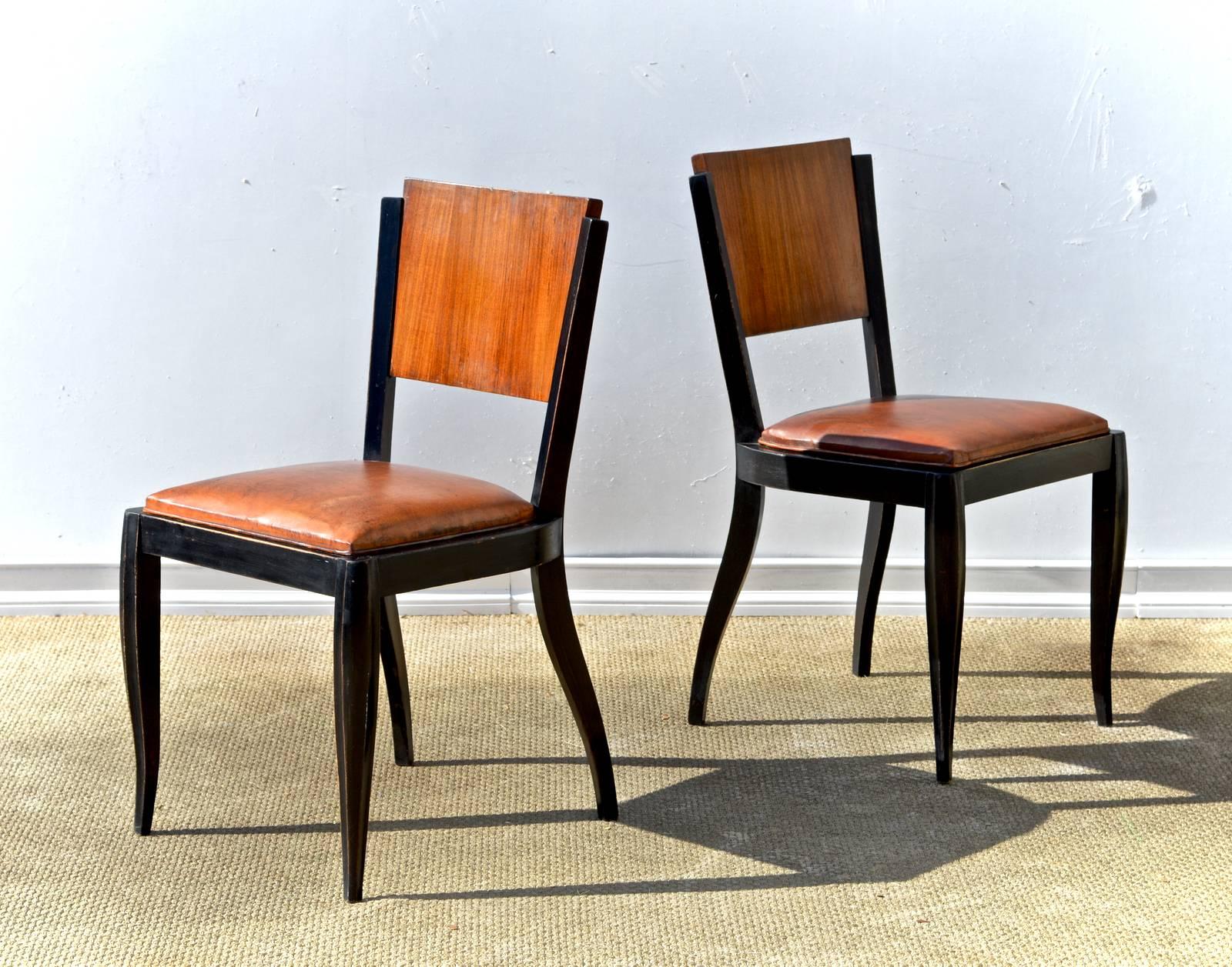 Pair of ebonized French side chairs in the Art Deco taste. Curvy legs and supple brown leather on the seats. Tre' chic.
 