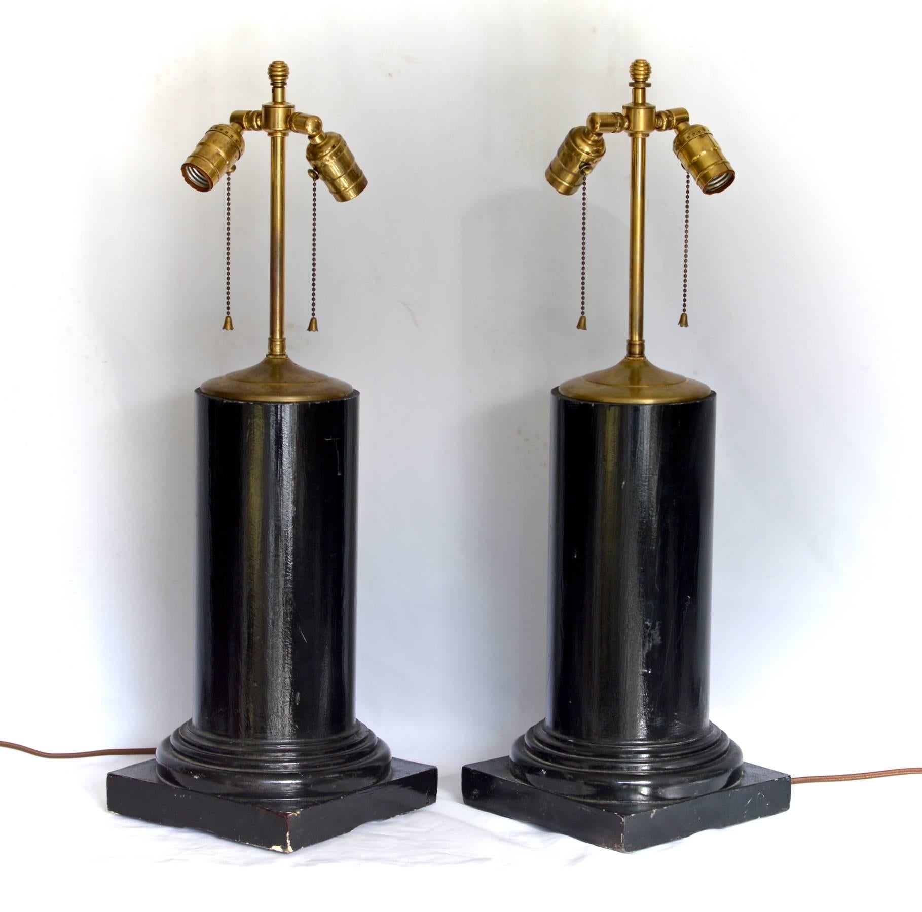 A stunning pair of ebonized column form table lamps having vintage brass double socket clusters and patinated brass vase tops. Just rewired with brown cloth wrapped cords, the architectural forms are ready to add a stately and classical look to any