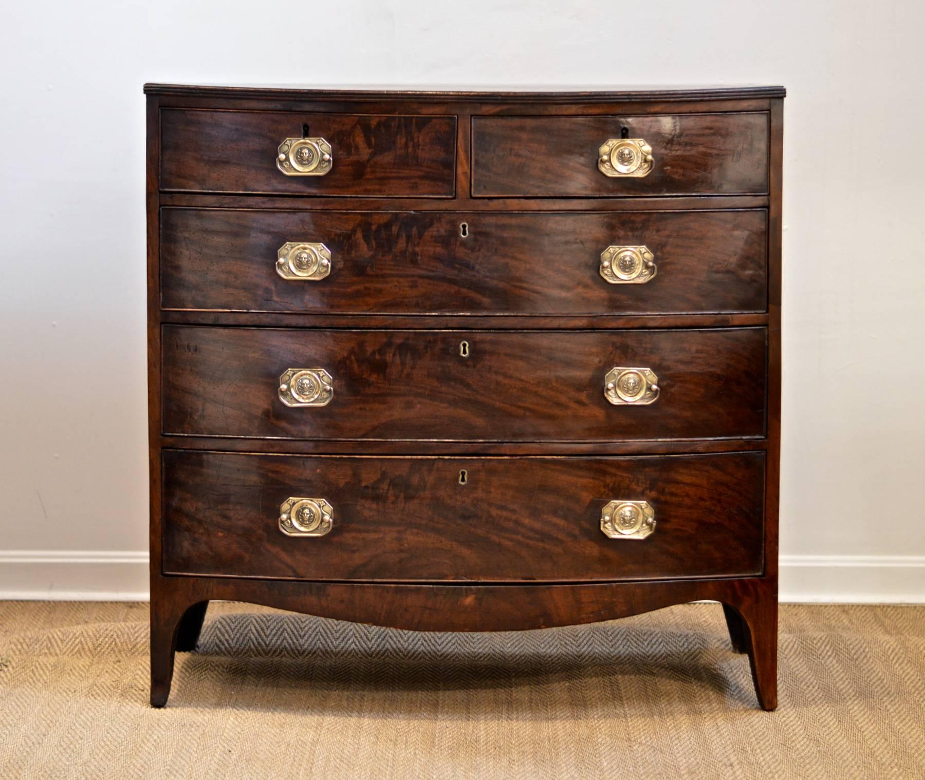 Period George VI bowfront chest of mahogany having rare brasses depicting the face of neptune. Perfect parts handsome and pretty, the two short drawers reside over three graduated long drawers that all function very well. This mid 19th Century