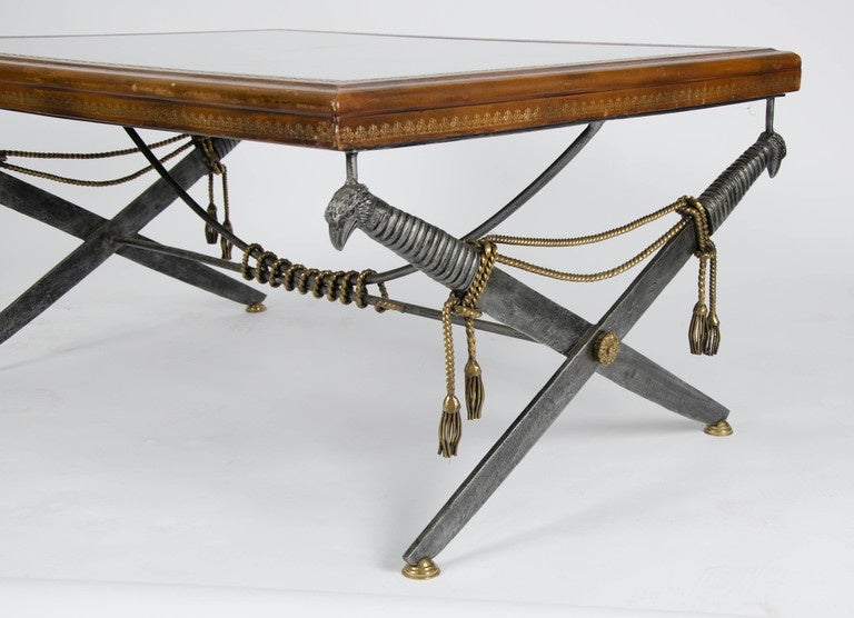 1940s coffee table with unusual simulated metal tassels and crossed swords metal base. The top is embossed with leather protected by a glass top.