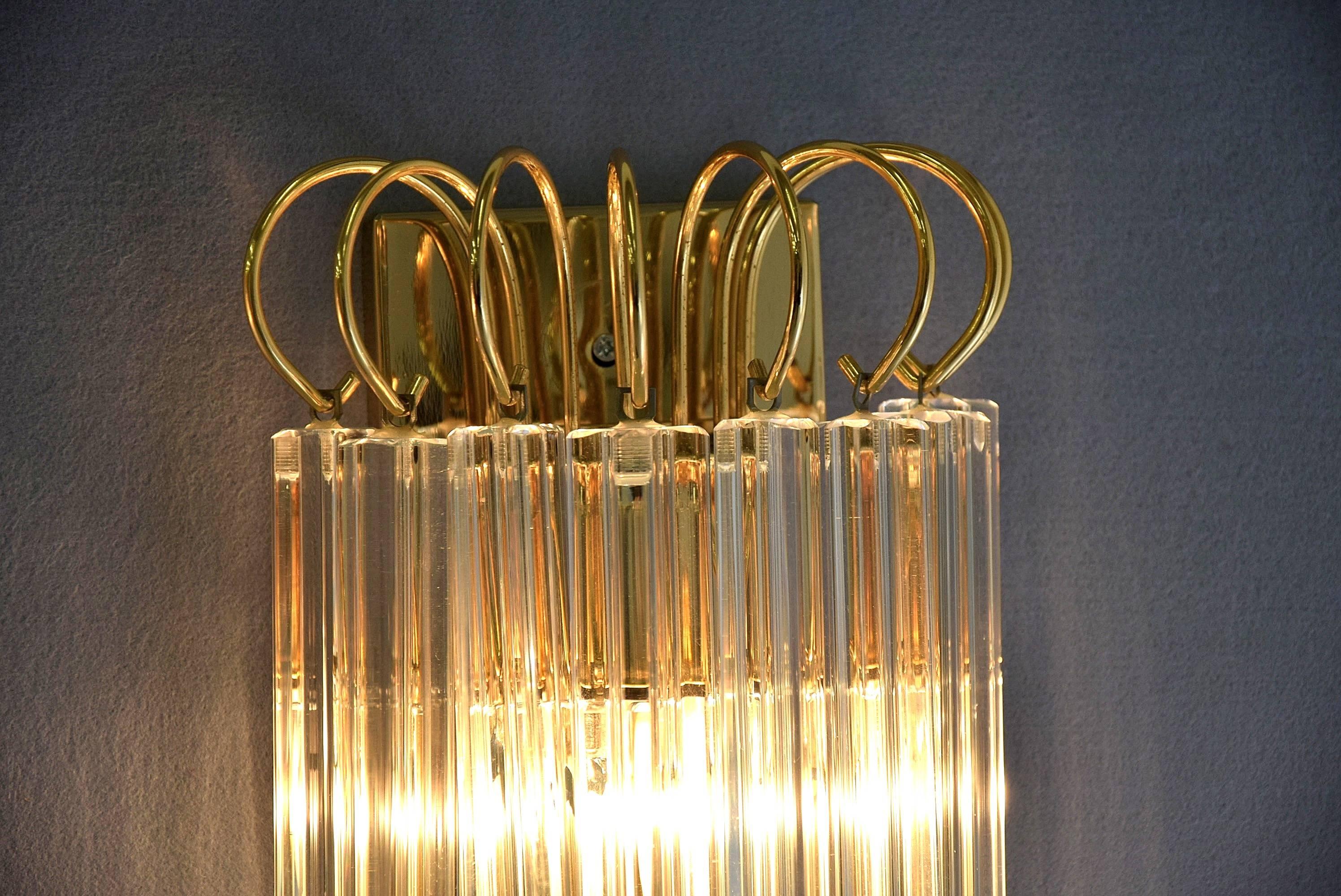 Beautiful shaped glass sculptures with two tiers of cascading clear glass prisms hanging from a brass frame. Provides a very nice and warm indirect light. Stunning wall object and light in one. 
In excellent condition.

 