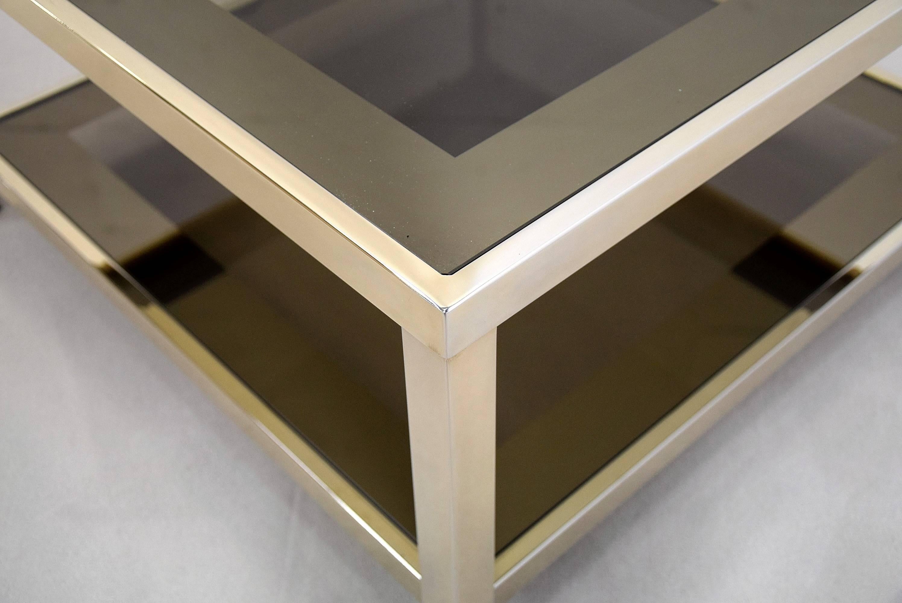 Stilvoller Mid-Century Modern vergoldeter zweistöckiger Couchtisch von Belgo Chrome, Belgien.

Die braunen Rauchglasträger haben einen verspiegelten Rand.

Der Tisch ist in sehr gutem Zustand.

Abmessungen: L.70 x B.70 x H.36cm.

Der Tisch wird in
