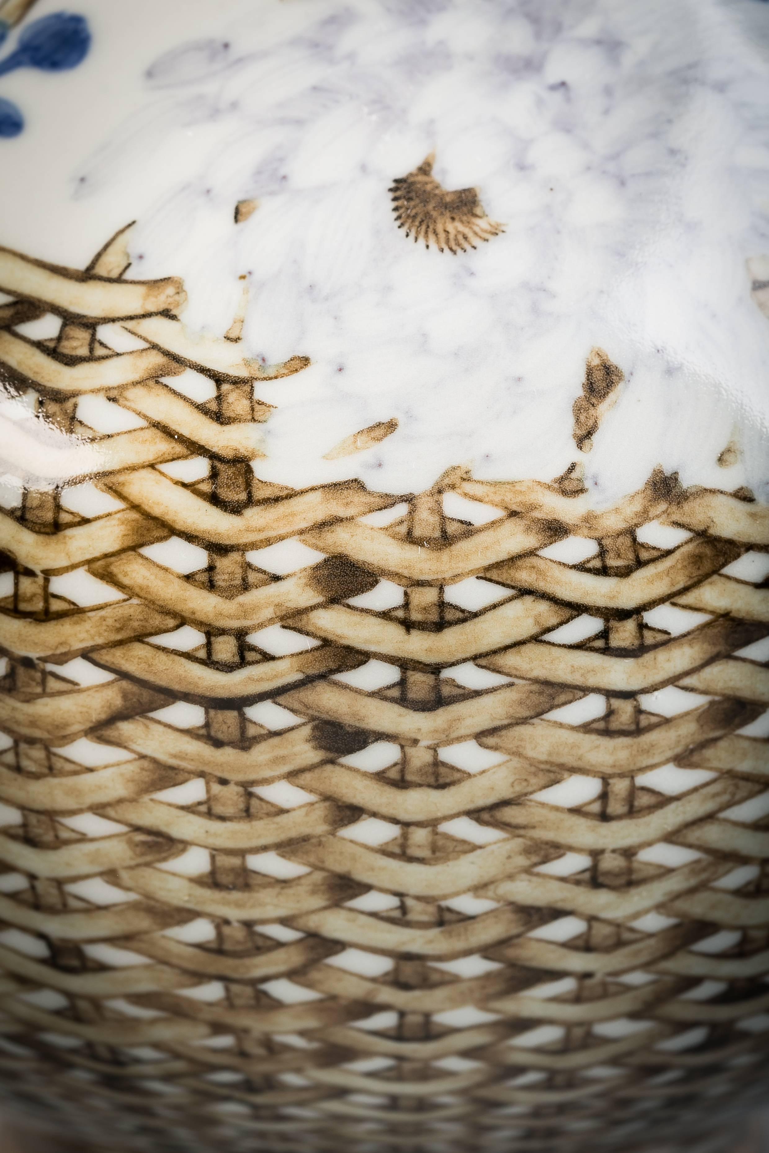 Depicting white and blue flowers in a brown basket. With underglazed blue mark. 
Makuzu Kozan.