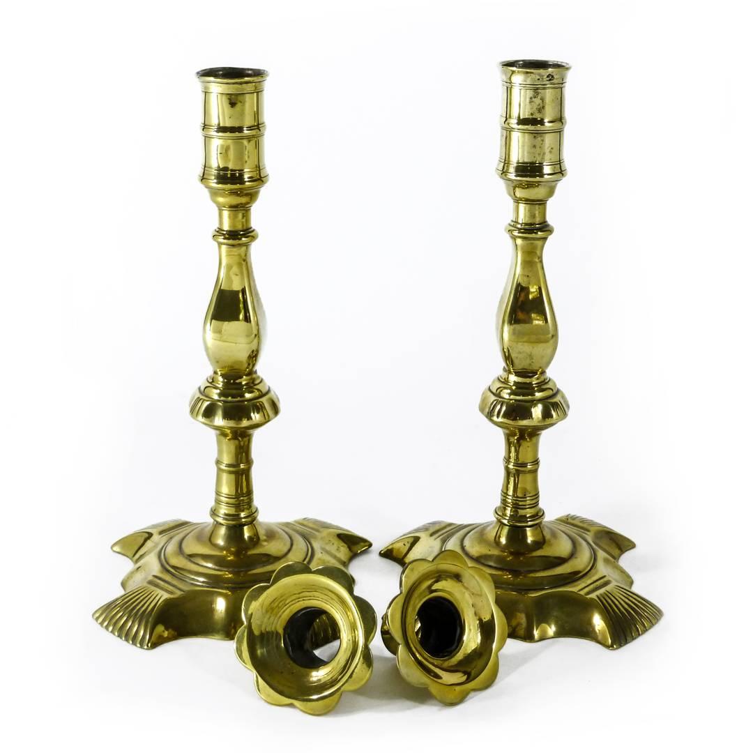 Unusual pair of English brass Queen Anne candlesticks. Shaped base with shell on each corner, circa 1765.

Originally silvered. Removable bobeche.

Measures: Height 9 1/2