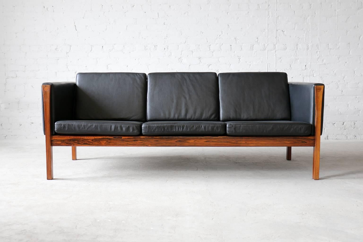 Model AP 63/3 (high variant of AP 62).
Brazilian rosewood frame.
Brand new aniline leather cushions.

Incredible vintage sofa designed by Hans Wegner for AP Stolen. This piece features an luxurious Brazilian rosewood frame as well as brand new