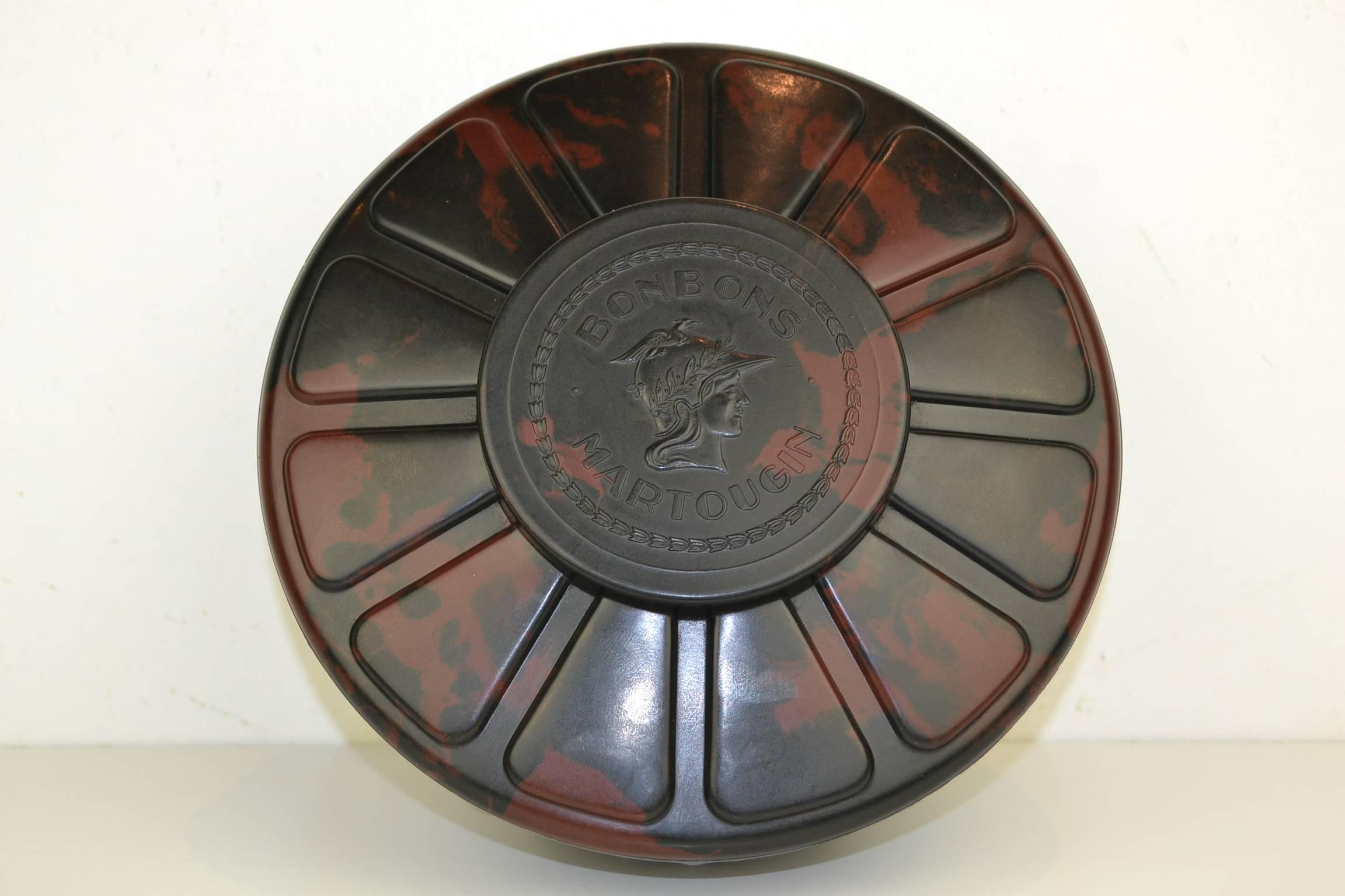 Stylish  Art Deco Bakelite Chocolate Box for Belgian Chocolate Martougin. 
This Chocolate Storage Box or Chocolate Gift Box dates from the 1920s. 
It's a beautiful Red with Brown flamed round bakelite box with Minerva Godess in relief on the cover