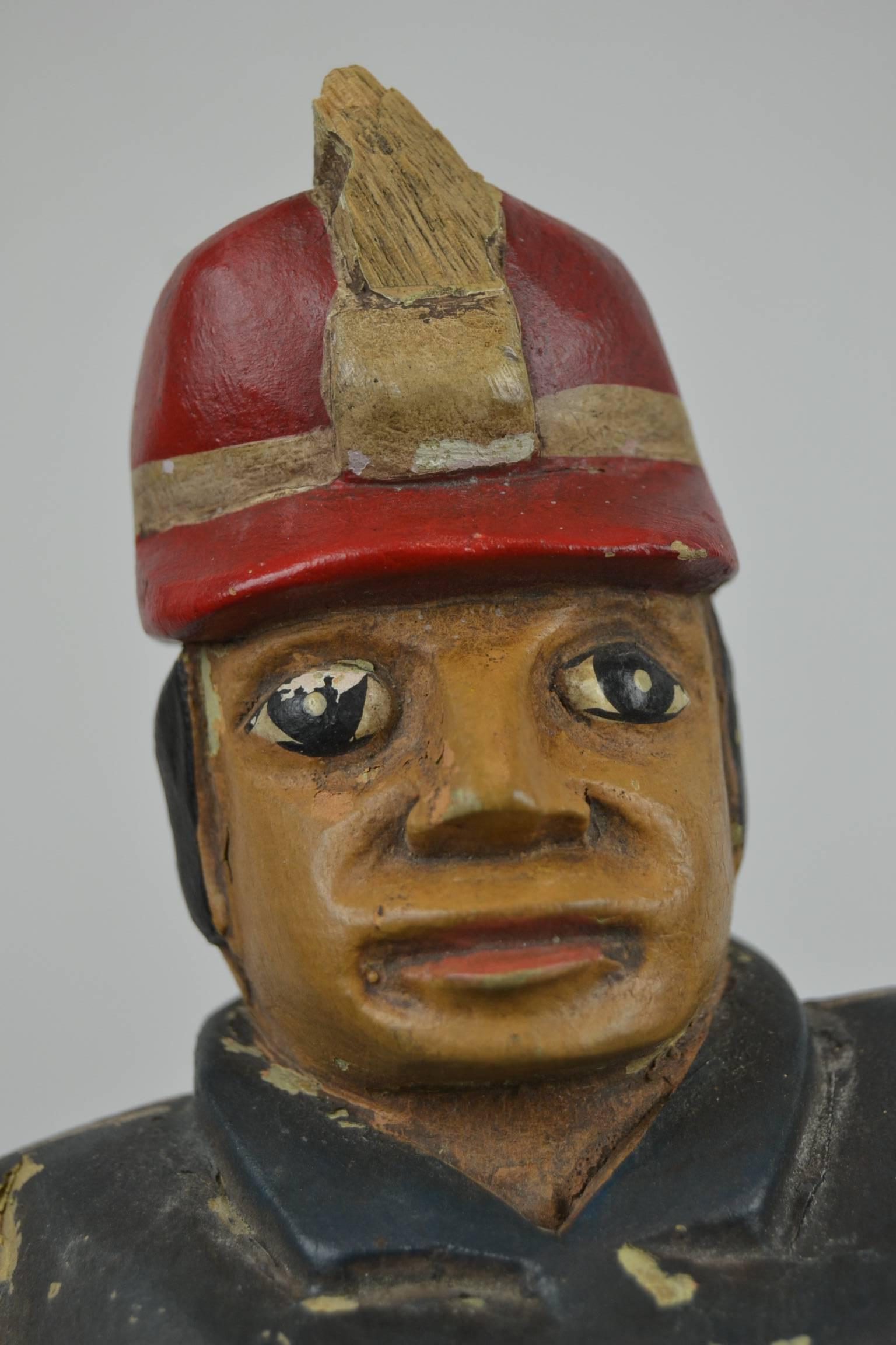 Stunning Folk Art wooden sculpture of a Fireman. 
This pre-war statue of a marching fireman or firefighter dates circa 1920-1930.
This fire-eater wears yellow with blue fire clothing, a red belt and a red with yellow helmet. Probably a fireman from