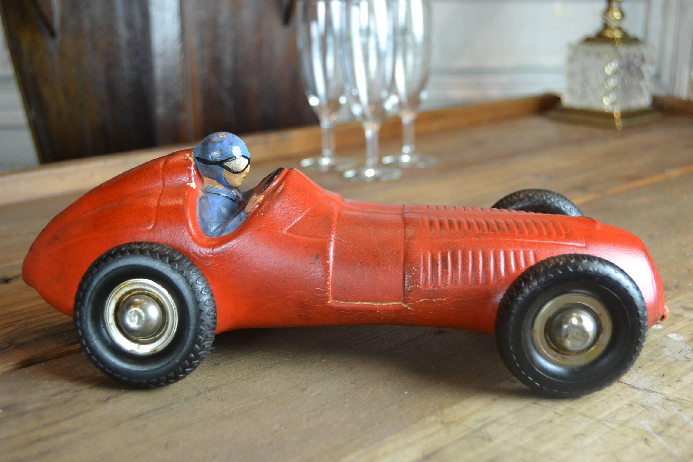 Thick Red Rubber Racing Toy Car - Racer Model Car . 
This Racer Car with Pilot dates circa 1940s.
Type : Ferrari - Maserati - Mercedes-Benz Race Car.
Black rubber Tires with Metal Hubs ( 1 is lost ).
Great old Patina . 

Stunning collectible Object