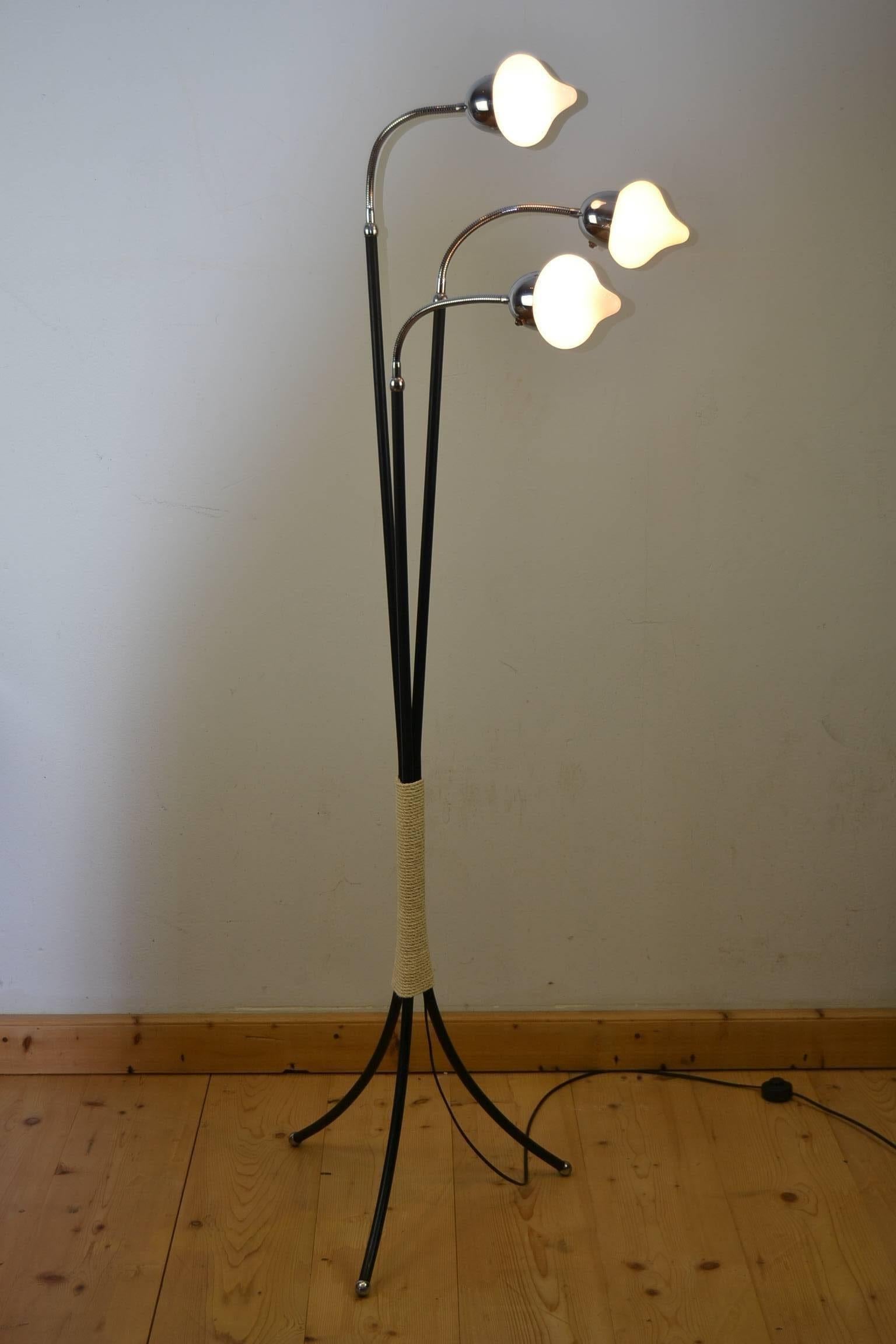 Vintage tripod modern floor light in the style of Stilnovo, Giuseppe Ostini, Reggiani.
1960s Scandinavian three-light lamp on tripod iron raffia wrapped base with chromed flexible arms and white glass shades. The arms can be oriented in any