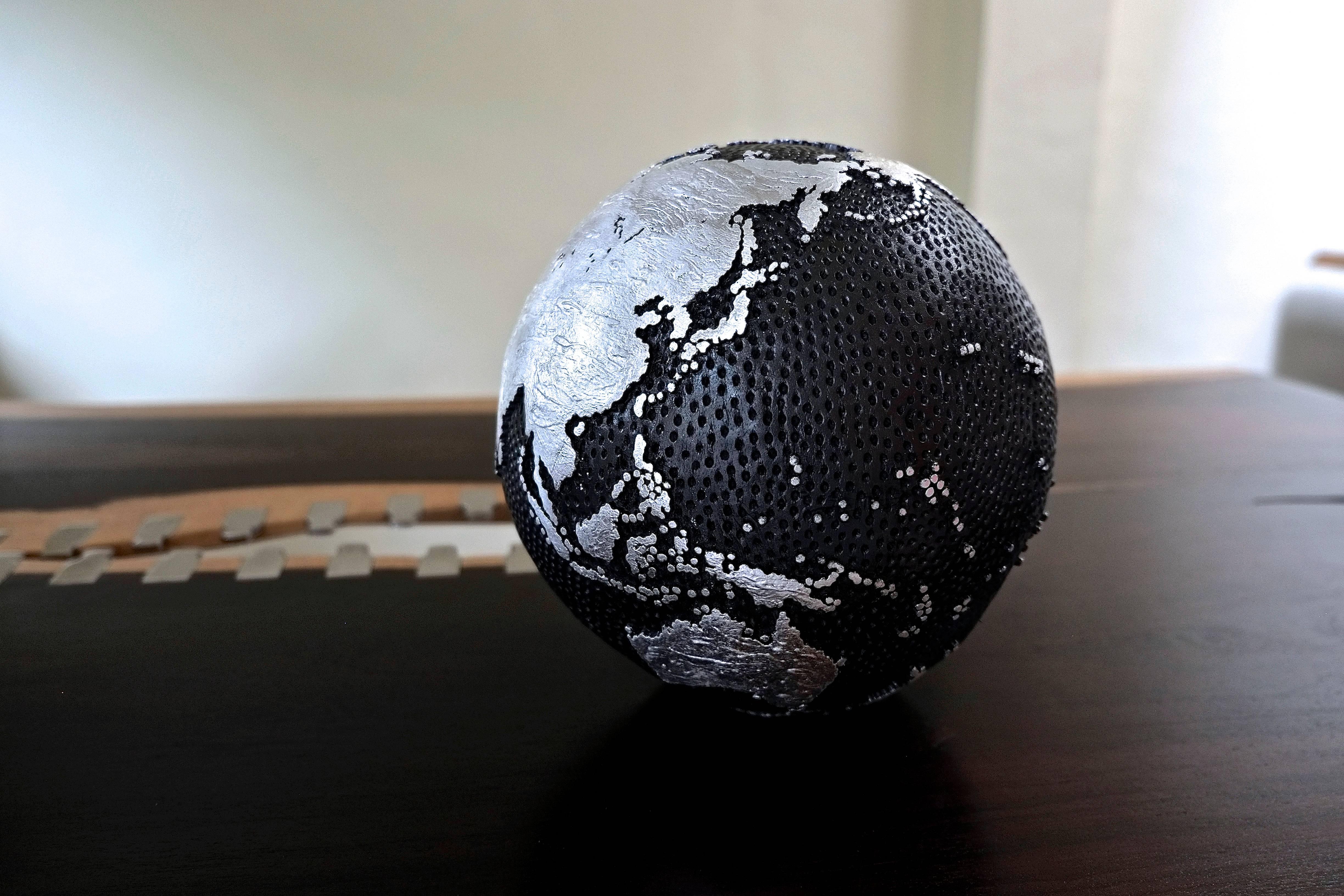 Wooden Globe 
Hand-carved 
Numbered 076 / 2017 
One of a kind 
Installed on a turning base . 
Oceans : 1000 Holes / Graphite 
Continents : Silver Leaf.