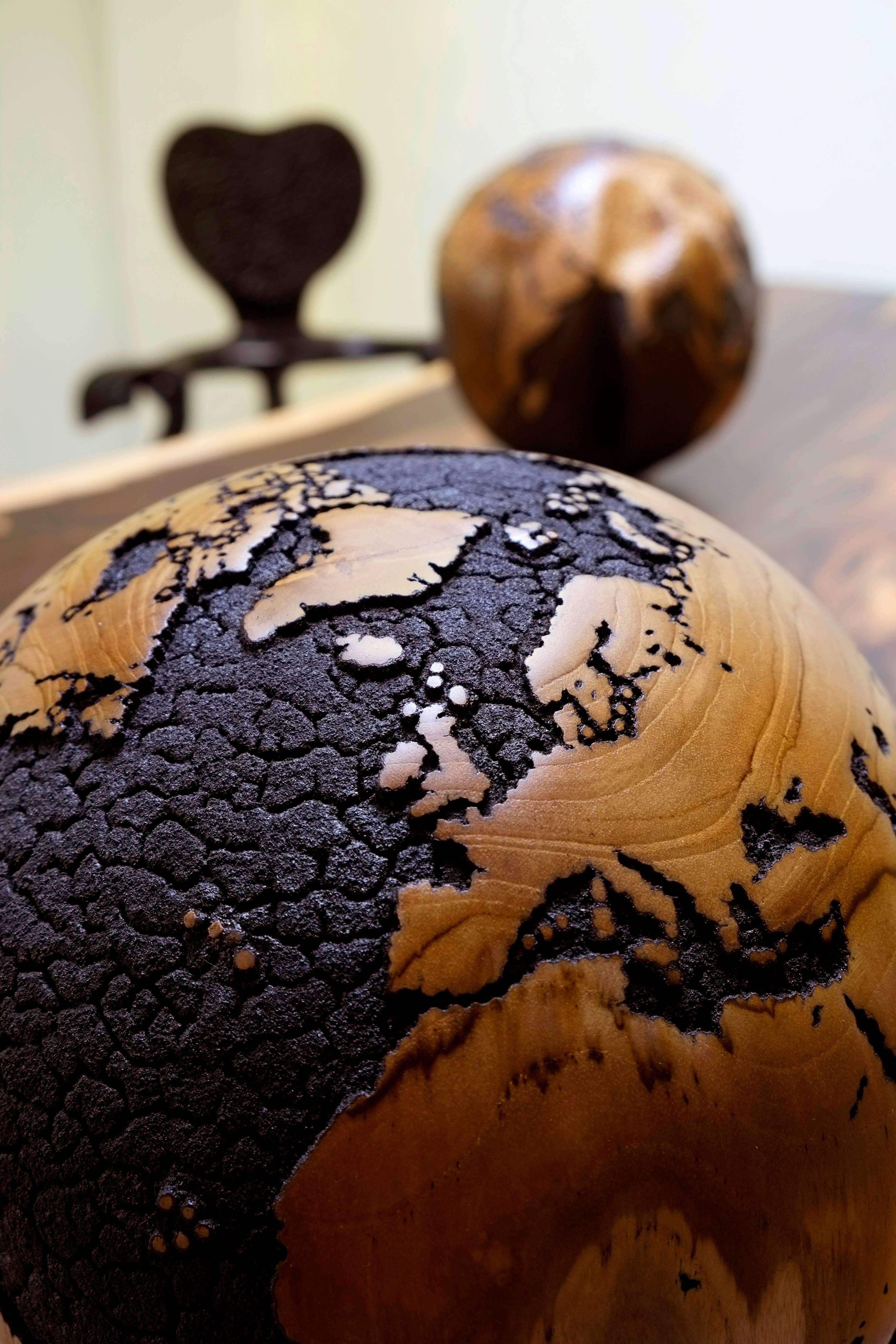 Wooden globe 30 cm hand-carved from teak root / turning base
One of a kind / Numbered / Signed HB
Hand-carved 
Cracked Oceans finishing black burned copper 
Natural continents.
 
