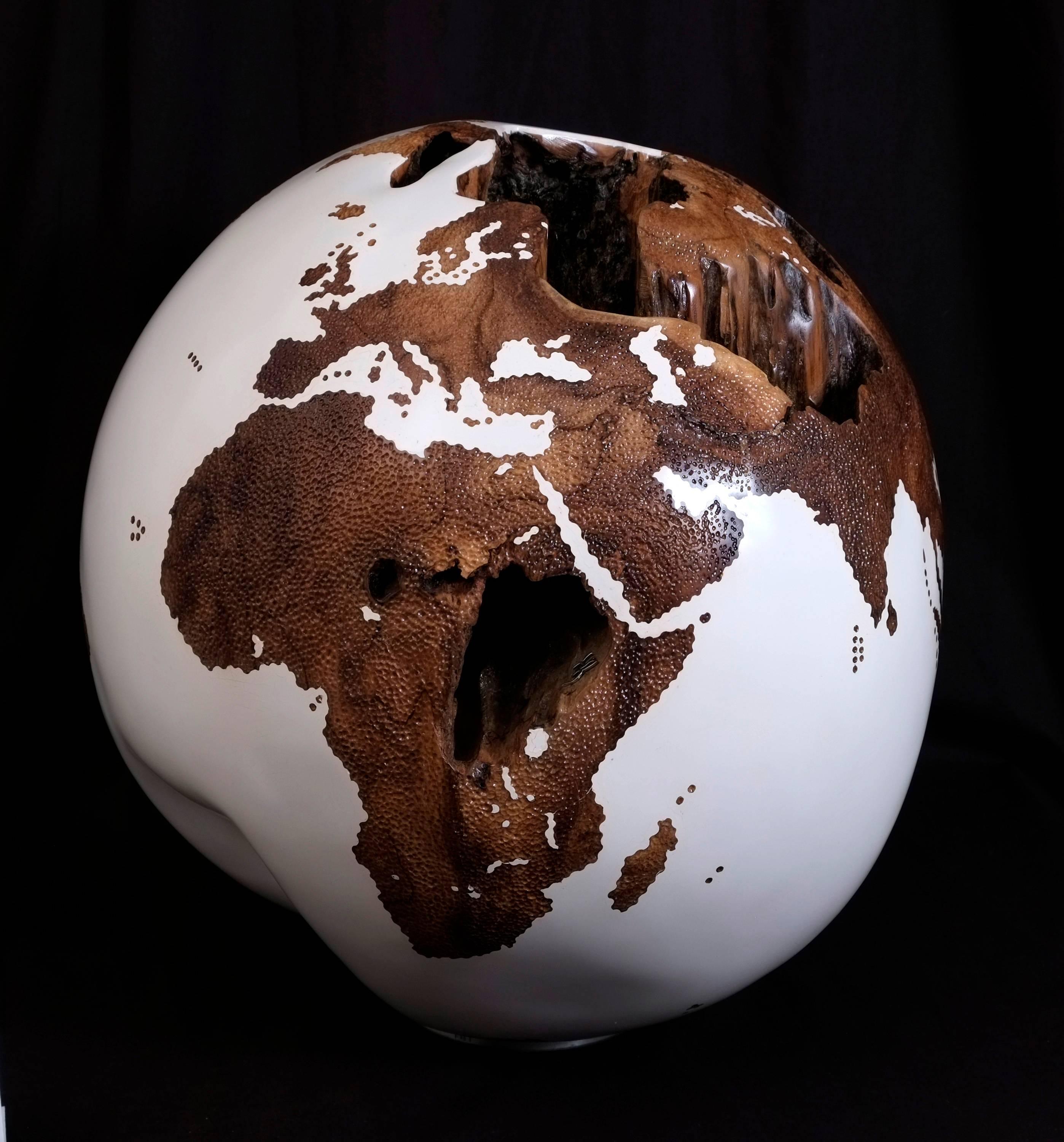 Mystery is the basic element of all works of art.

Stunning hand-carved wooden globe made of reclaimed teak root in acrylic white resin finishing and hammered skin effect, with a striking natural feature that resembles a mysterious volcanic
