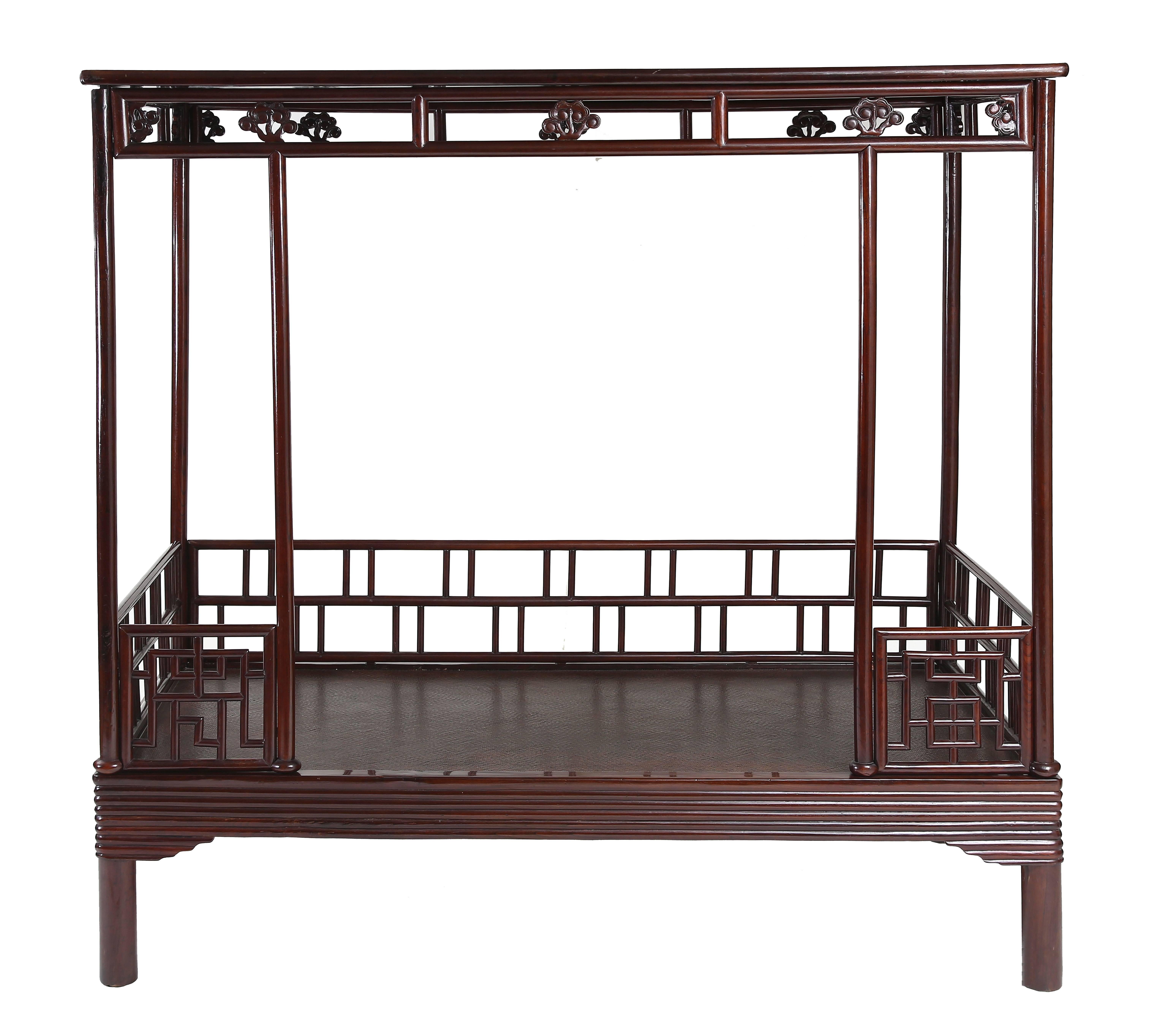 The bed frame enclosing a cane top and decorated with wrapped-around lipped molded edges and spandrels, supported on circular-sectioned legs; the six posts braced on the back and sides by railings of fretwork, two short railings flanking the opening
