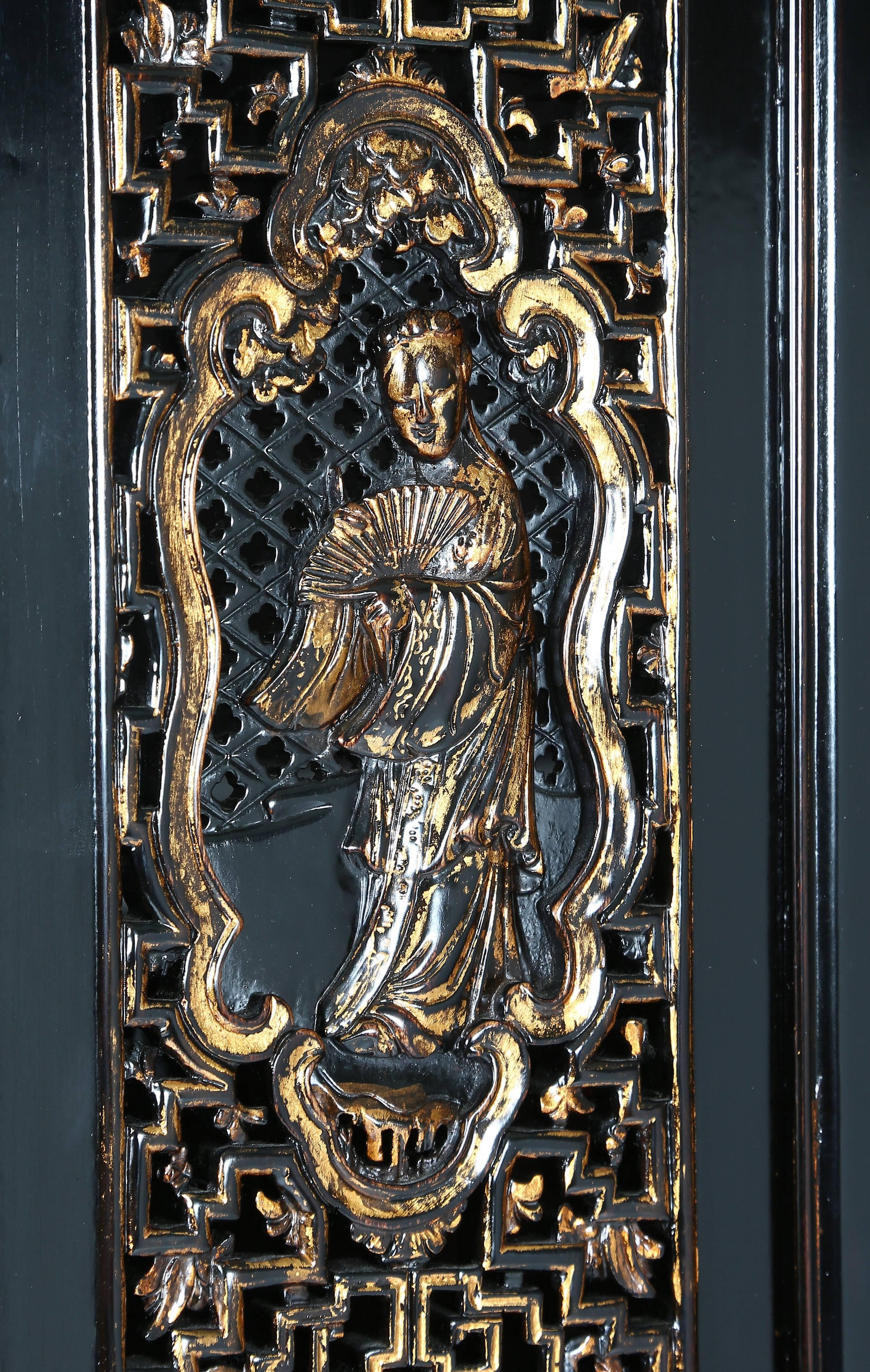 The fine cabinet decorated with gilt open-carved panels of figures above plain panels on the four bi-fold doors, above a row of three drawers, the side panels with open geometric fretwork, raised on square-sectioned legs with front cusped spandrels