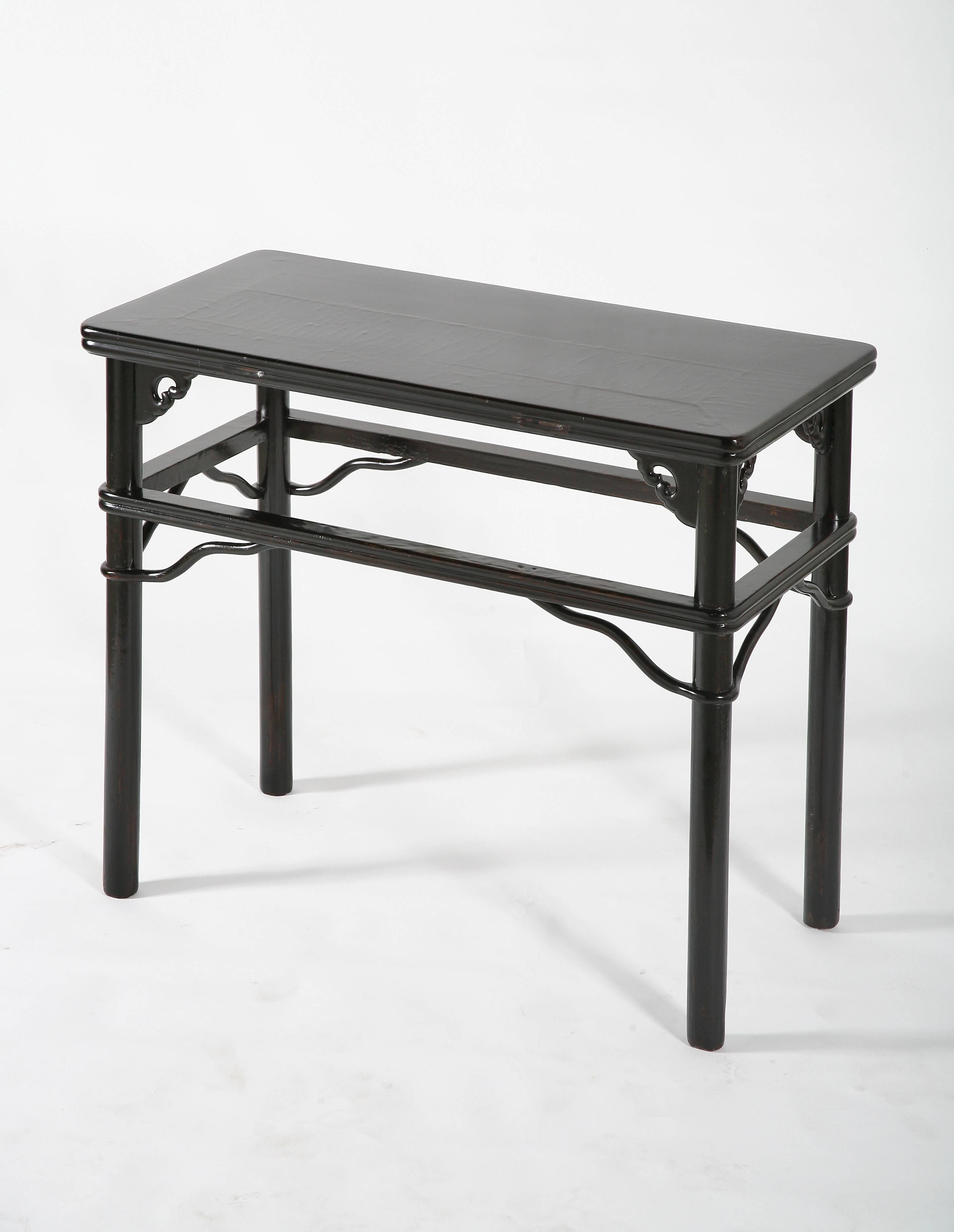 The aged crackled lacquer top with a floating top panel, enclosed within a frame carved with double molded edges, supported on straight circular-sectioned legs flanked by open-carved ruyi spandrels, wrapped-around double molded straight stretchers