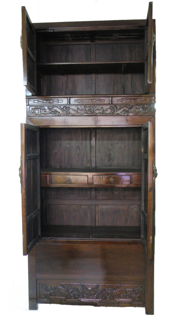 Of rectangular form, the magnificent cabinet consisting of two sections with the top chest stacking on the lower cabinet, each section with a pair of well-figured door panels, the top doors surmounting a row of three horizontal panels relief-carved