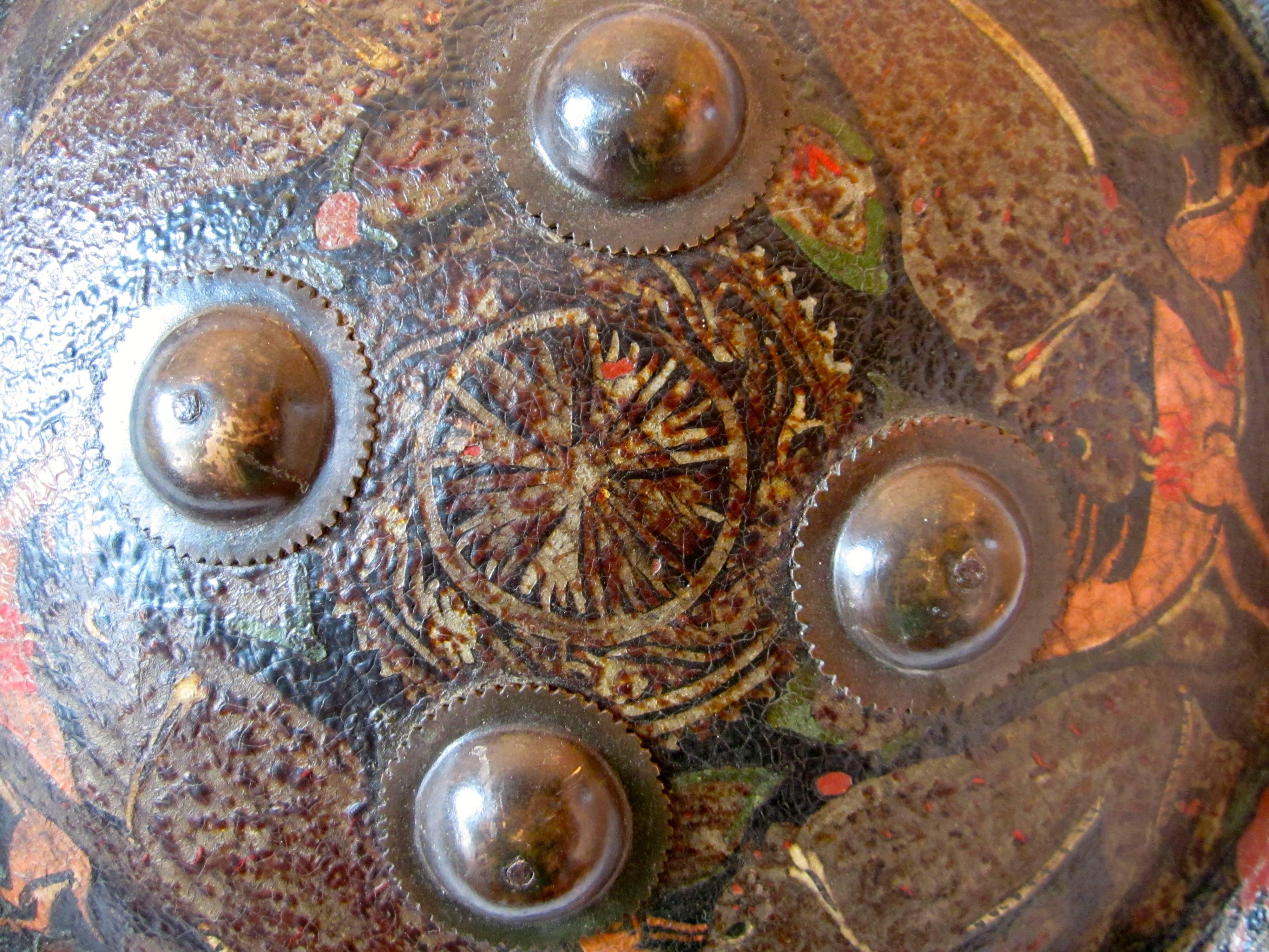 Painted dhal shield made in leather with four brass studs, convex polychrome structure depicting leopards hunting deers. Sign of use.