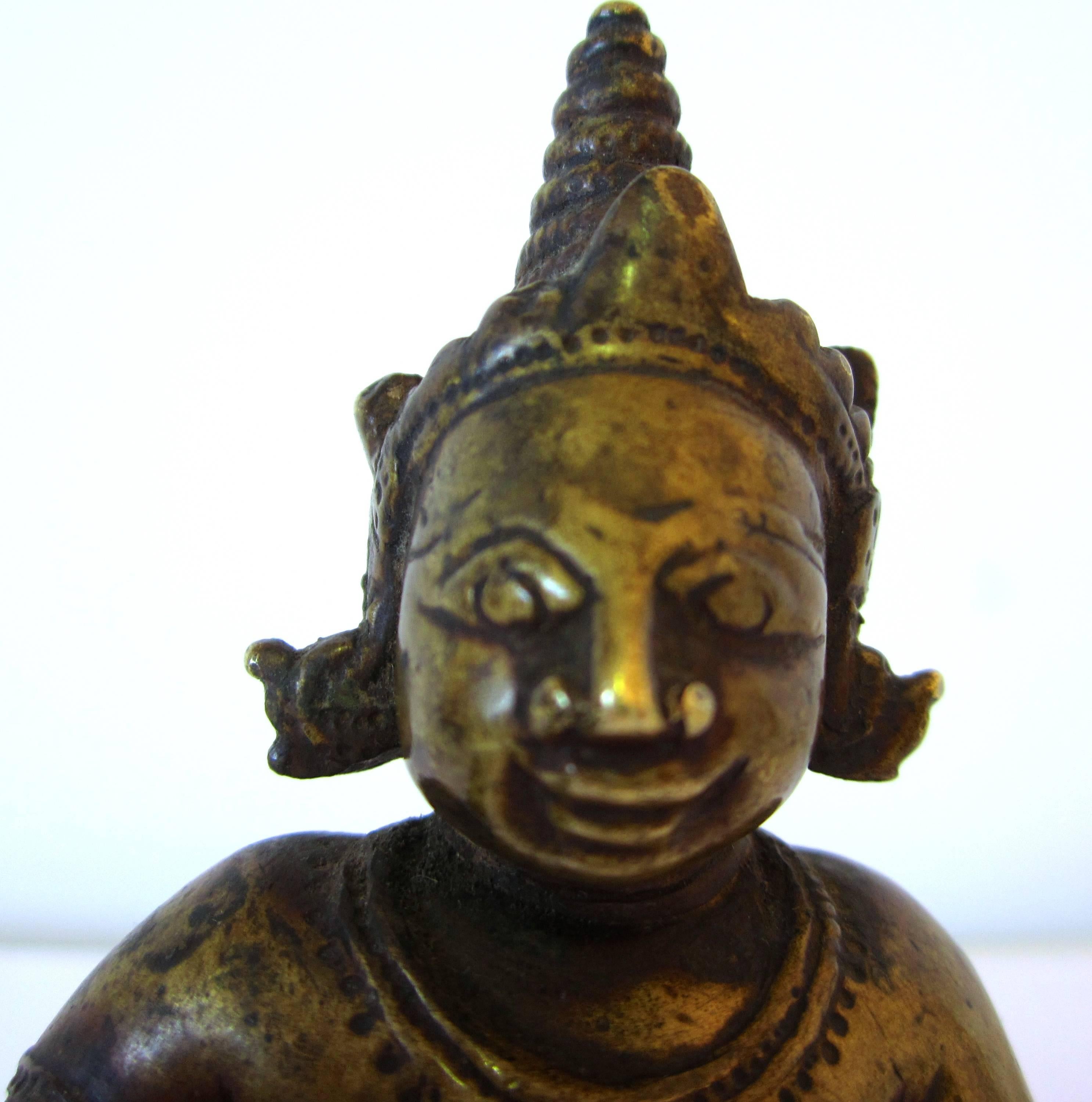 Indian bronze figure of baby Krishna as "Butter Thief," holding the butter ball he stole from his stepmother. Wearing jewelry and a crown, Orissa, 17th century.