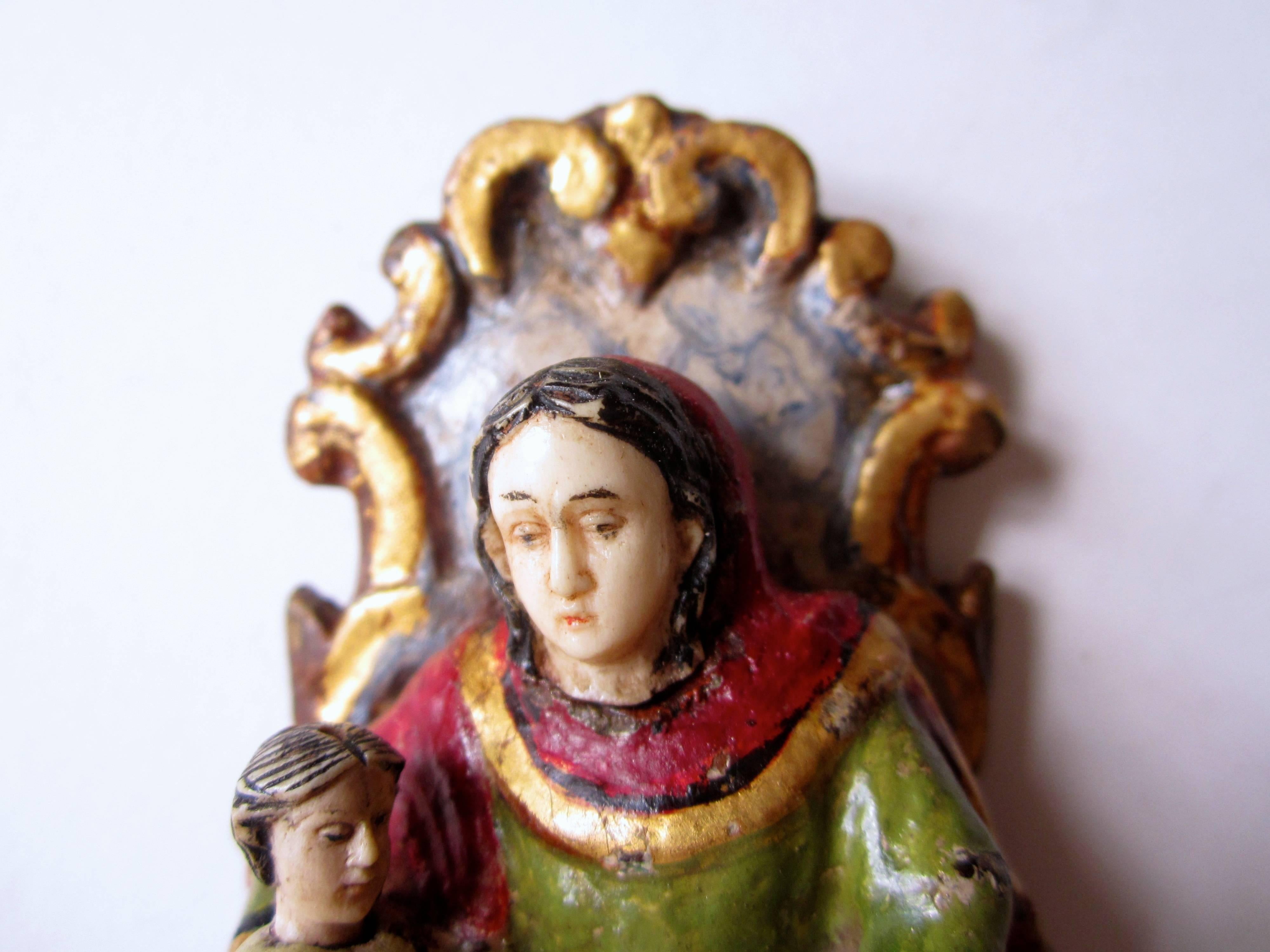 A small and fine Indo-Portuguese figure of Saint Anna, mother and teacher of Lady Mary. Carved, painted and giltwood, the faces and hands of Saint Anna and of the child Mary and the book are carved in bone, Goa, 18th century.