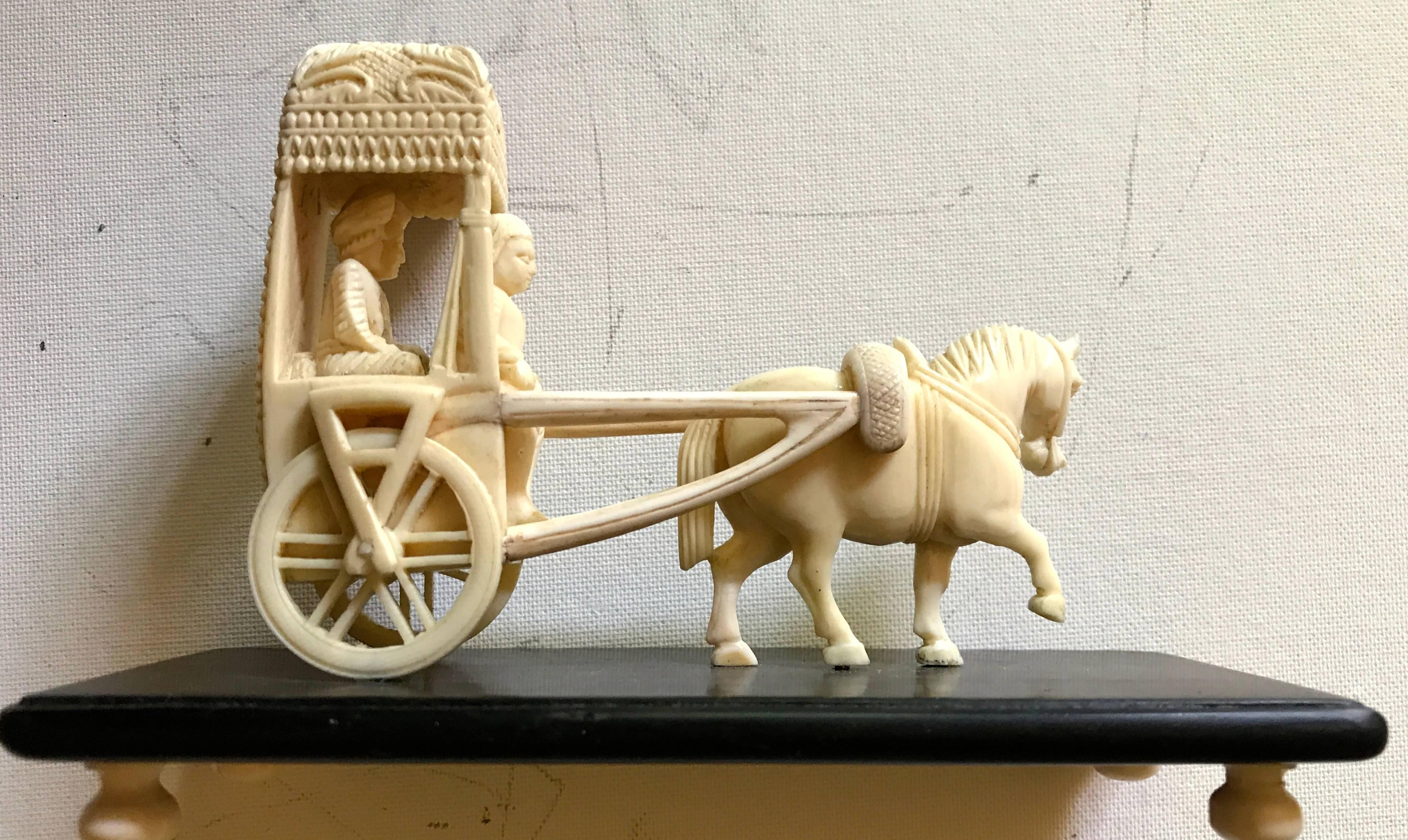 A small Indo-European (company style) fine carved bone group of a chariot and horse, with rider and passenger, on a ebony base with bone feet. India, late 19th-early 20th century.