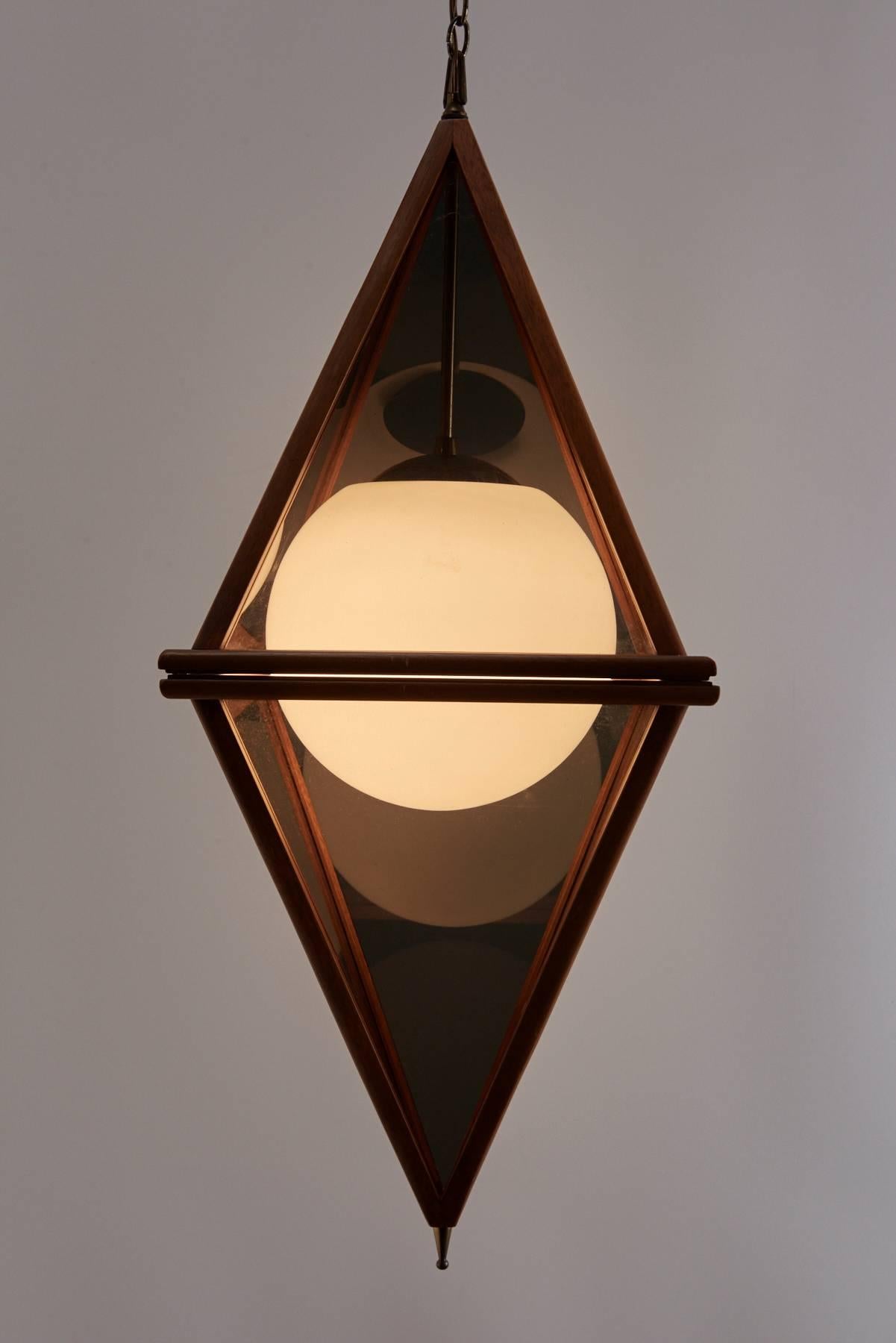 Diamond shaped pendant lamp with teak frame, smoked acrylic panels, opaque glass globe and brass detailing. Brass chain measures approximately 15 feet. Beautiful mid-century styling.