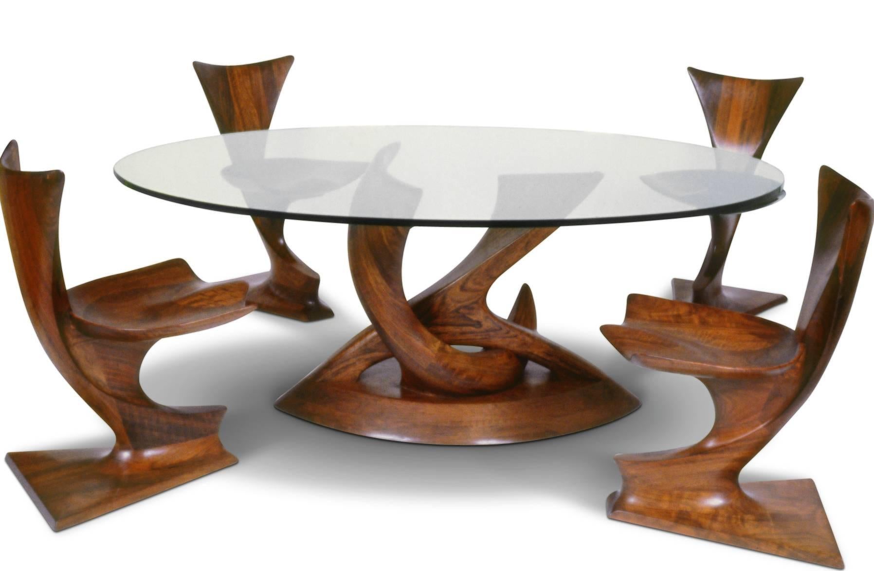 The pedestal of this dining table is laminated and carved from solid Mozambique and affixed to the base with a steel, threaded rod. Round glass top.

