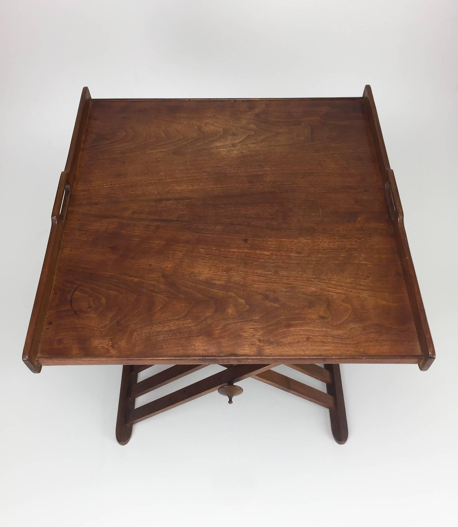 Folding Campaign tray table in walnut with carved handles and decorative finial at leg axis. Designed by Stewart MacDougall for Drexel.