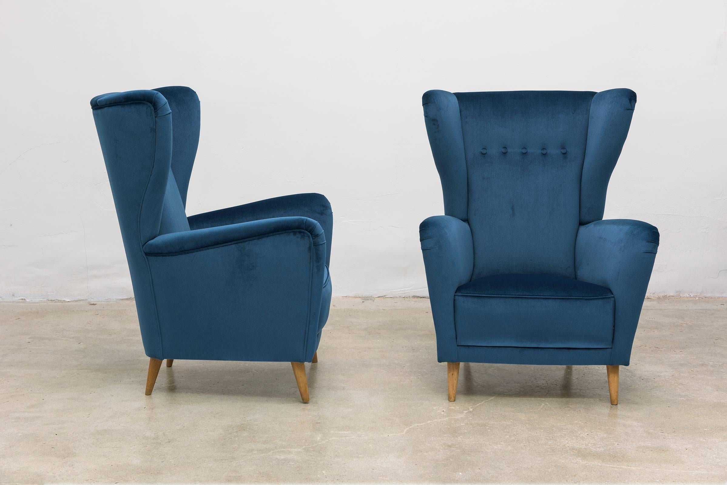 Gorgeous pair of high-backed Italian armchairs. Recently recovered in blue velvet, with maple legs.