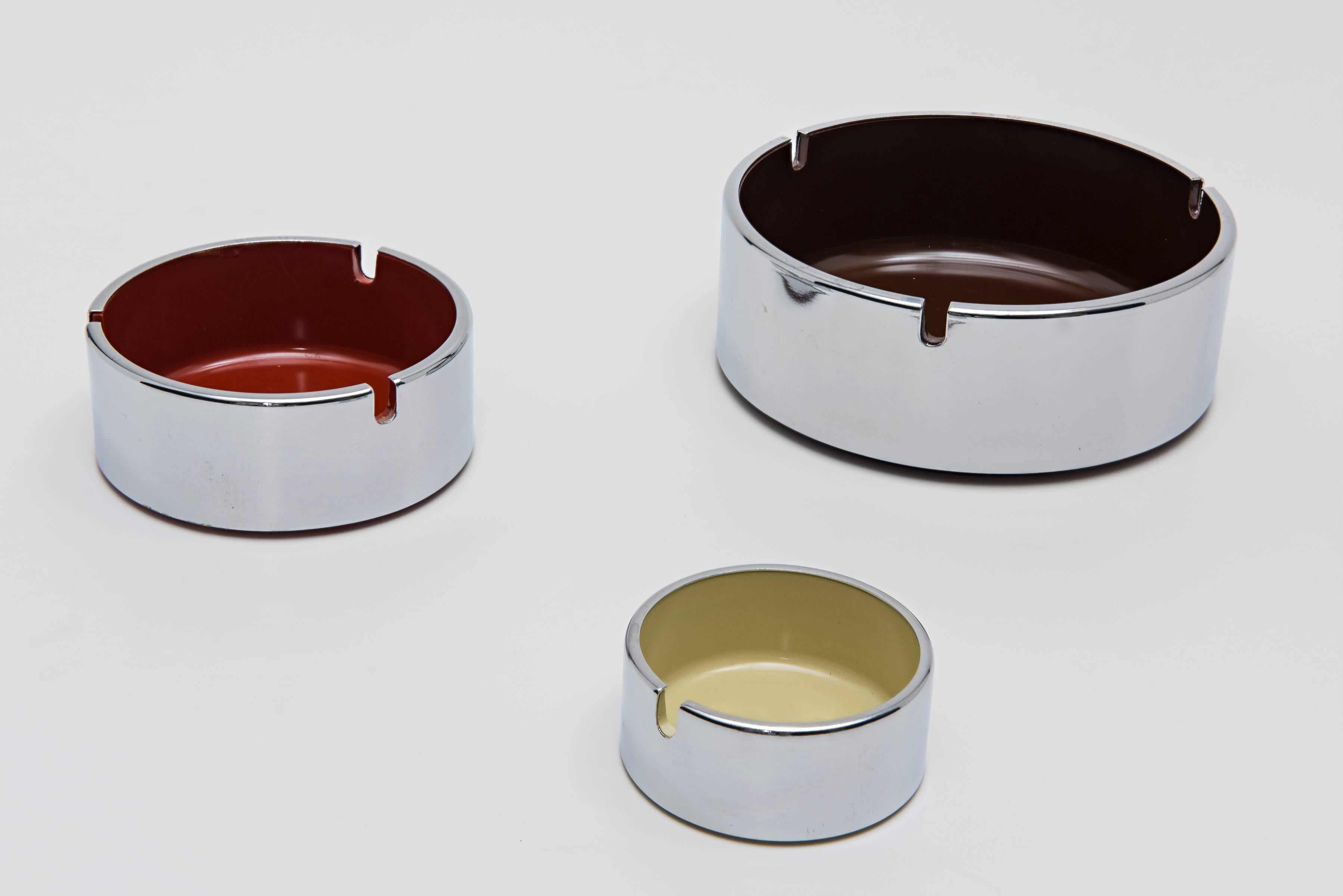 Beautiful set of polished stainless steel ashtrays, descending in size, with moulded plastic wells in brown, cream and burnt ochre. Underside of each moulded with 