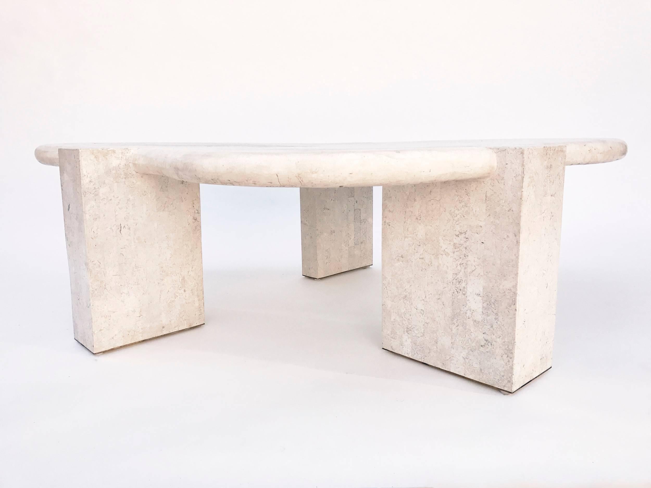 Tessellated stone biomorphic coffee or cocktail table by Maitland Smith, from the 1970s. Fine tilework in fossilized stone covers the top of this biomorphically shaped coffee table. Three rectilinear modernist legs in contrasting tessellated pattern