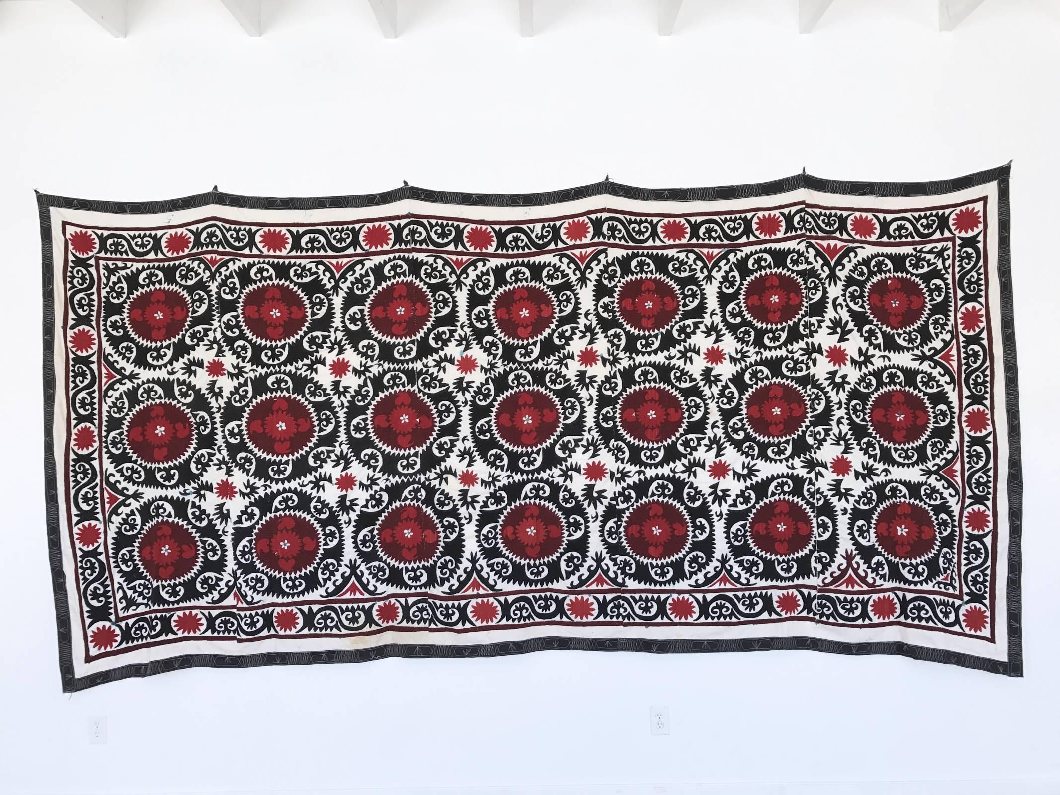 Intricate hand-embroidered needlework Uzbek Suzani with red, black and white geometric and paisley motifs throughout. Black border with white detailing. Linen and cotton with silk threading. Very large size, can act as a bold wall hanging, bedspread