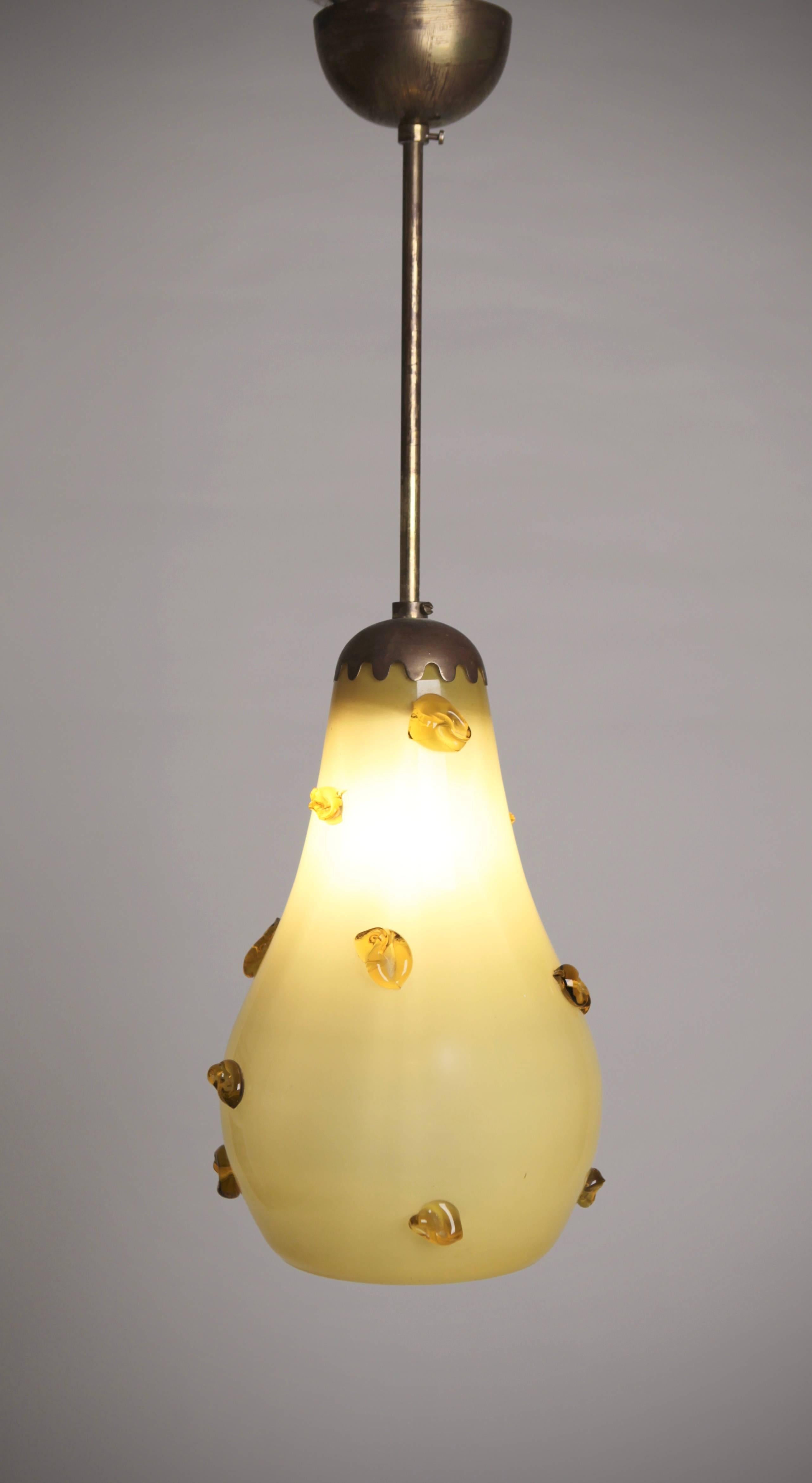 Eine birnenförmige Deckenleuchte aus gelbem, überfangenem Glas, mit Tropfen aus geschmolzenem Glas und Messingbeschlägen,
im Stil von Paavo Tynell, hergestellt in Finnland, ca. 1940er Jahre.
 