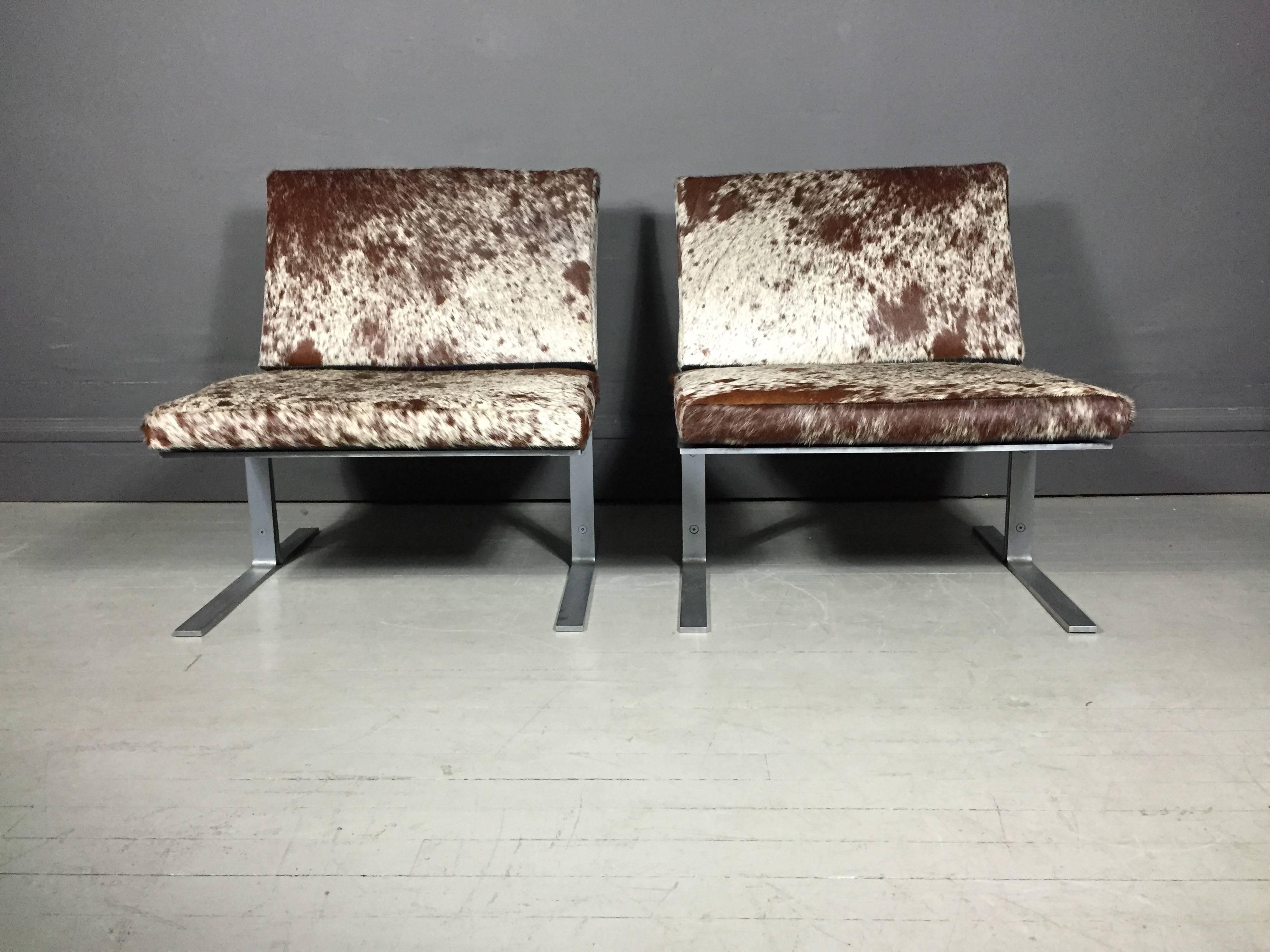 A chic pair of lounge chairs with flat-bar chromed steel frame, black rubber supports and recent upholstery of Brazilian cowhide. Perfection USA, circa 1970.